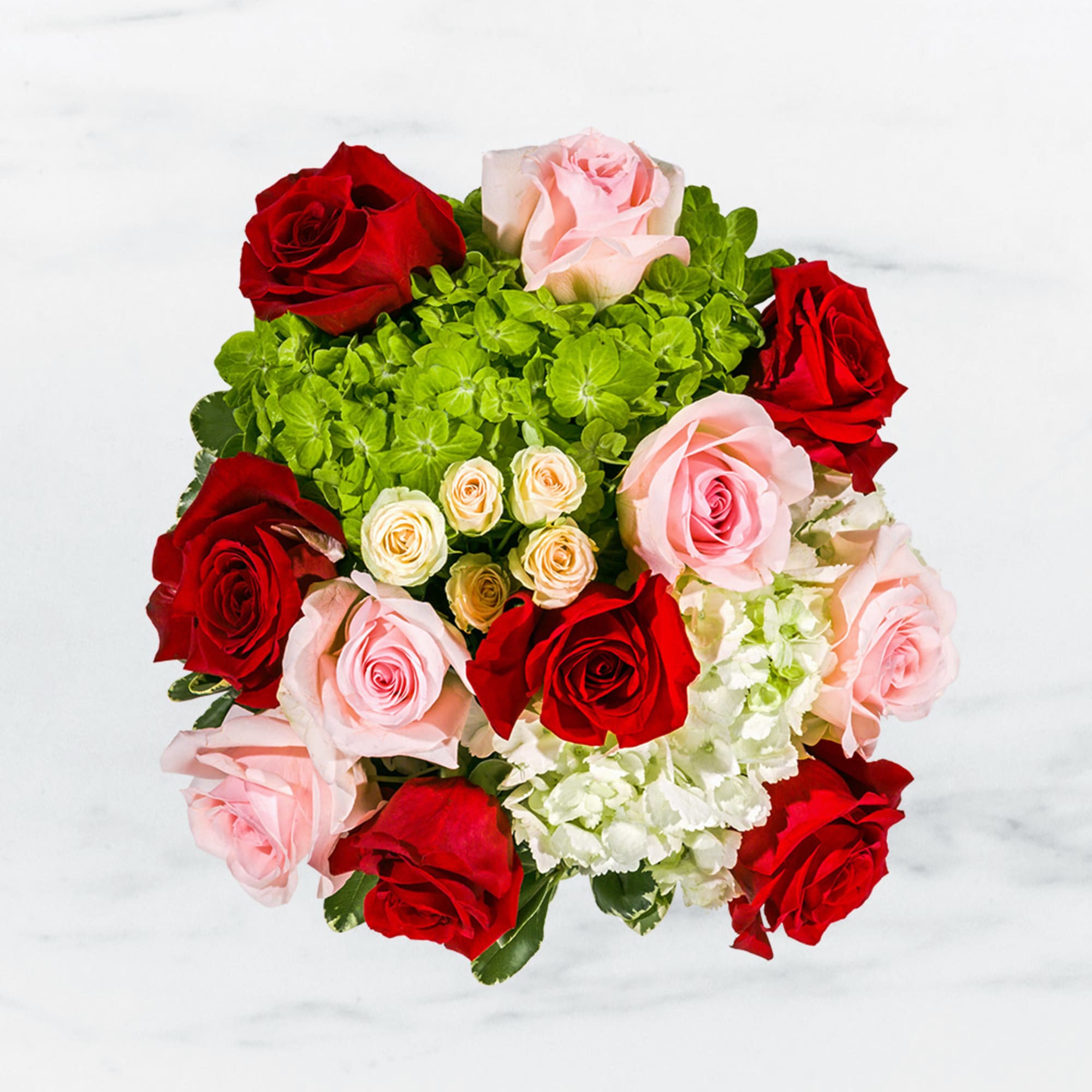 This arrangement includes pink roses, red roses, spray roses, and hydrangea. it