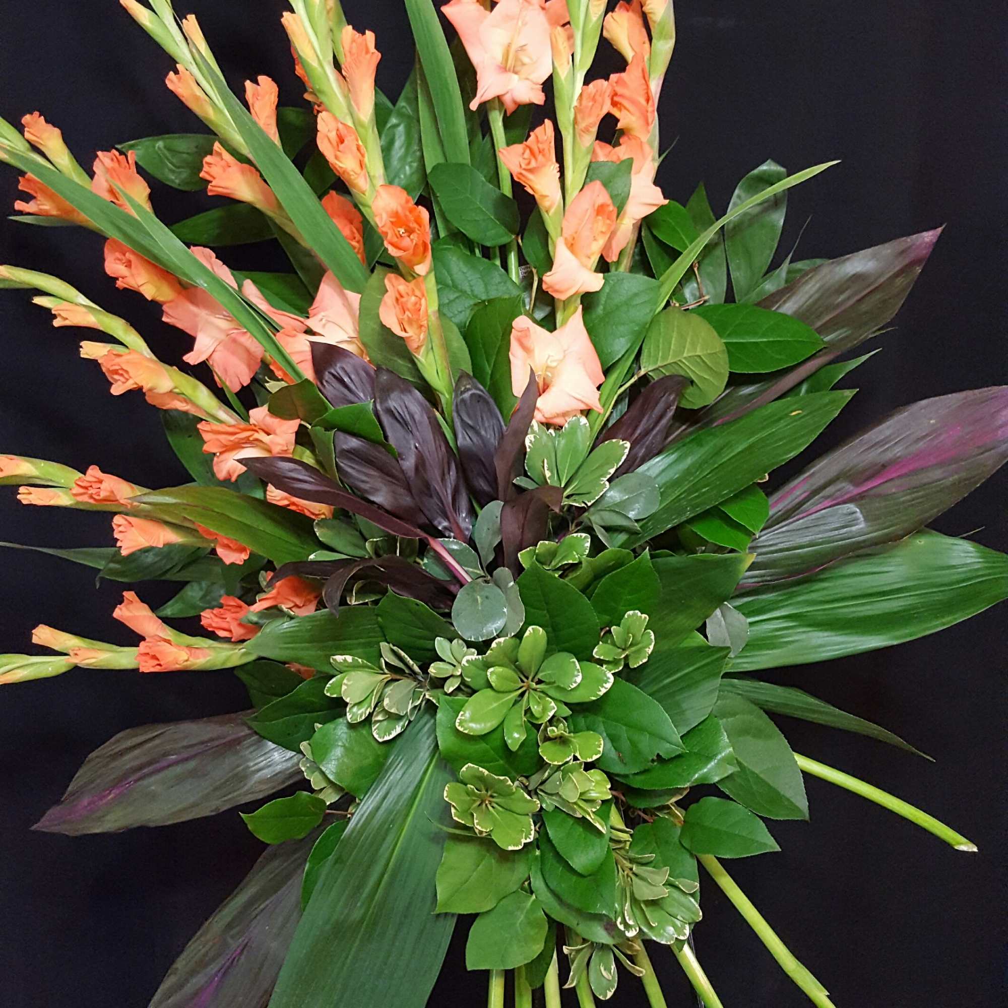 This standing spray features a fan of gladiolus and aspidistra mixed with This standing spray features a fan of gladiolus and aspidistra mixed with