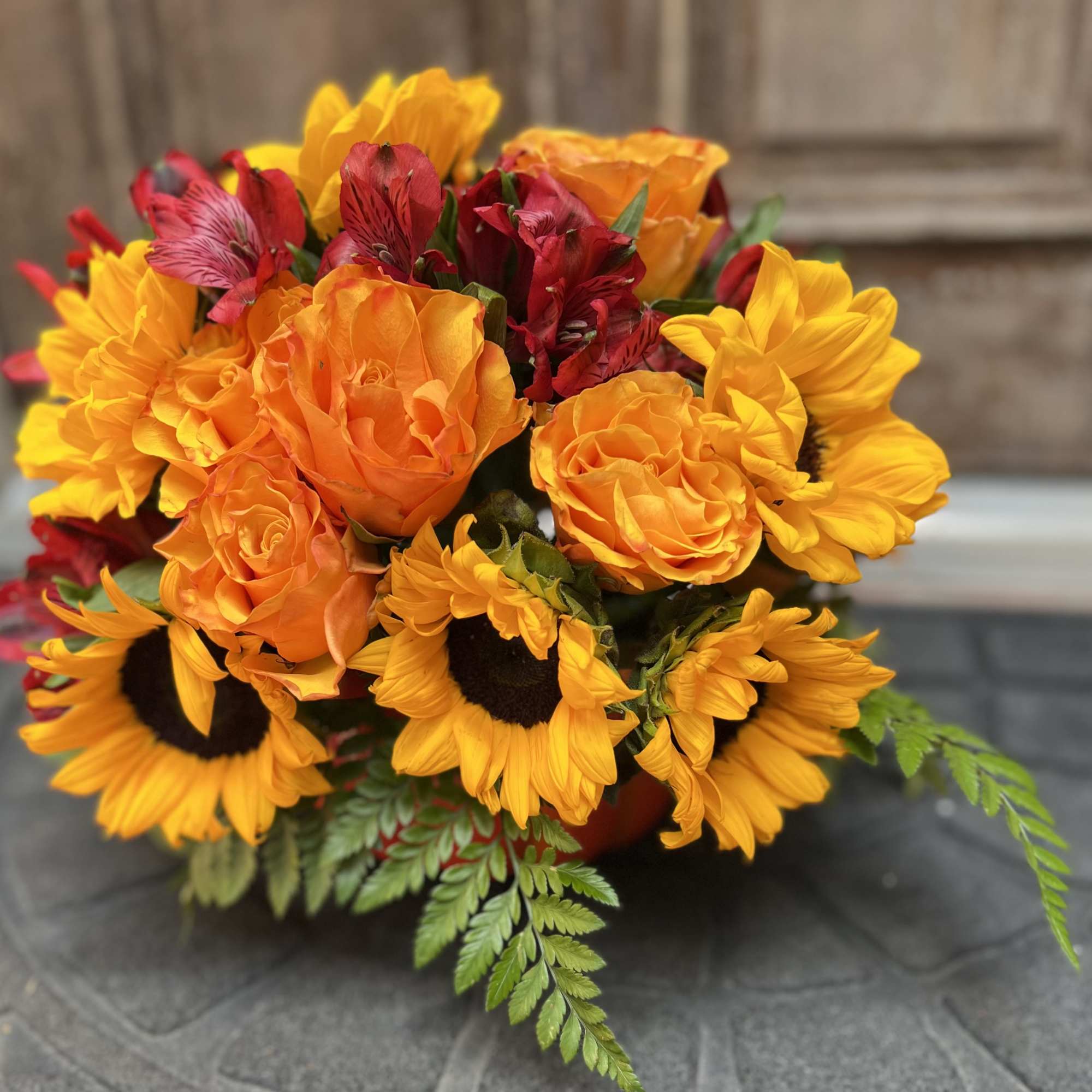 Designers Choice of an array of orange roses, bold and bright sunflowers