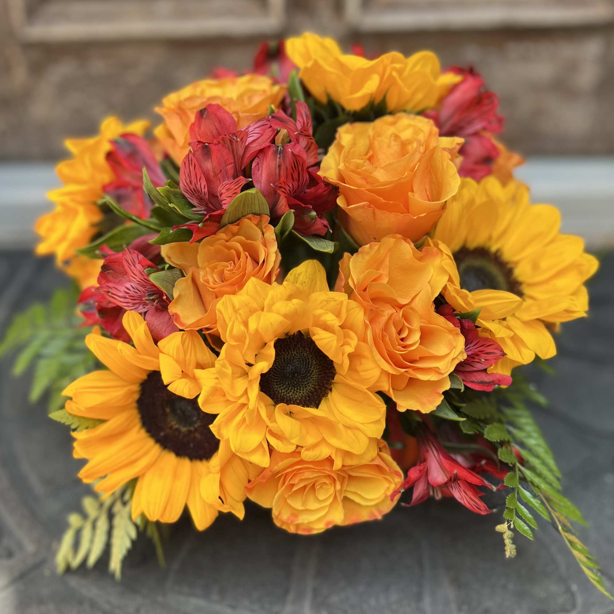 Designers Choice of an array of orange roses, bold and bright sunflowers