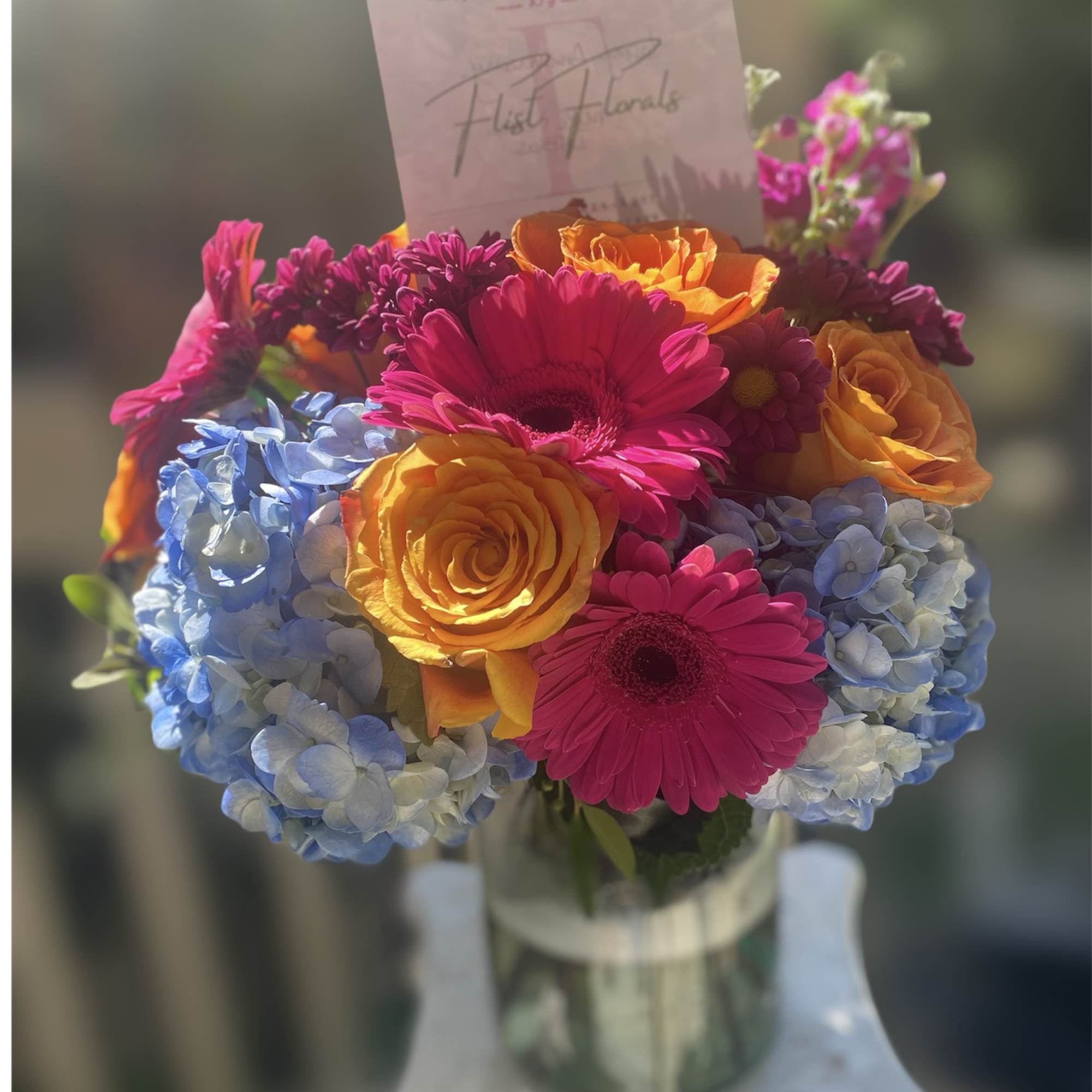 With the mixture of hot pink gerb daisies, orange roses and blue With the mixture of hot pink gerb daisies, orange roses and blue