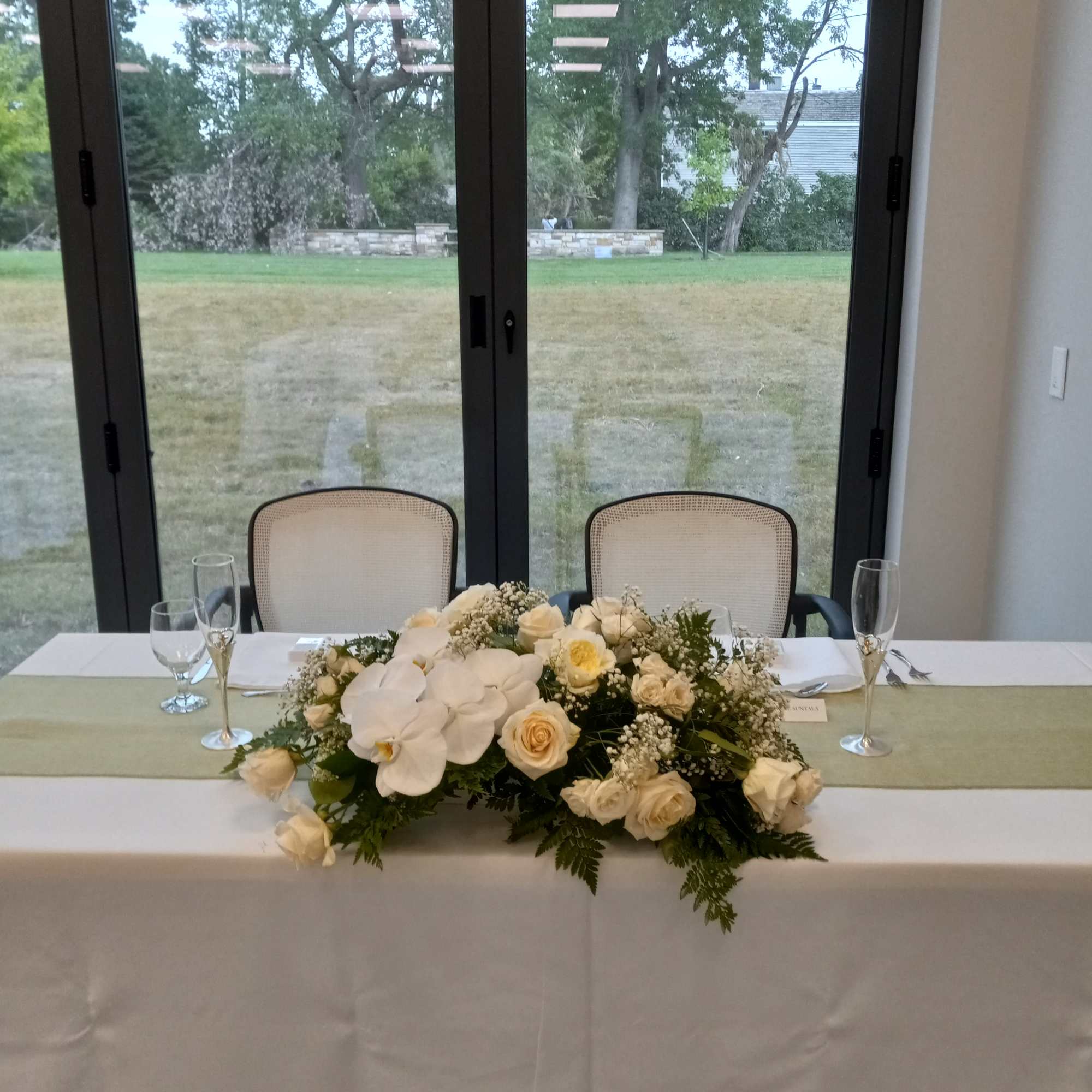 Beautiful phalaenopsis orchid, white roses, carnations, spray roses and greens sweetheart table