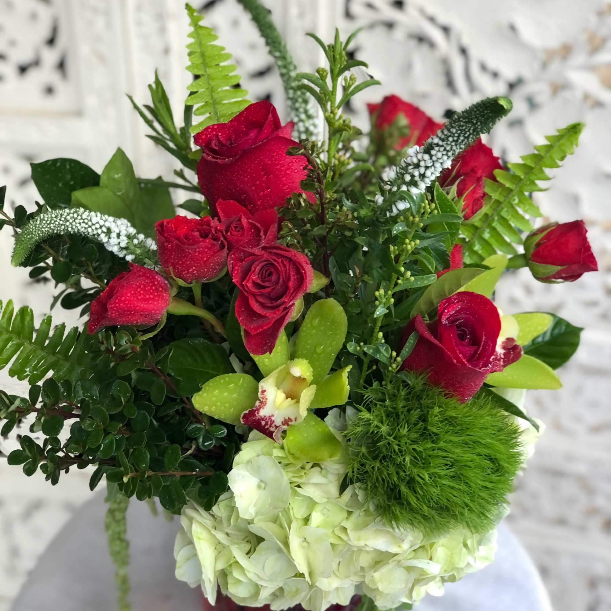 Vibrant red roses and spray roses arranged with delicate, white veronica, luscious