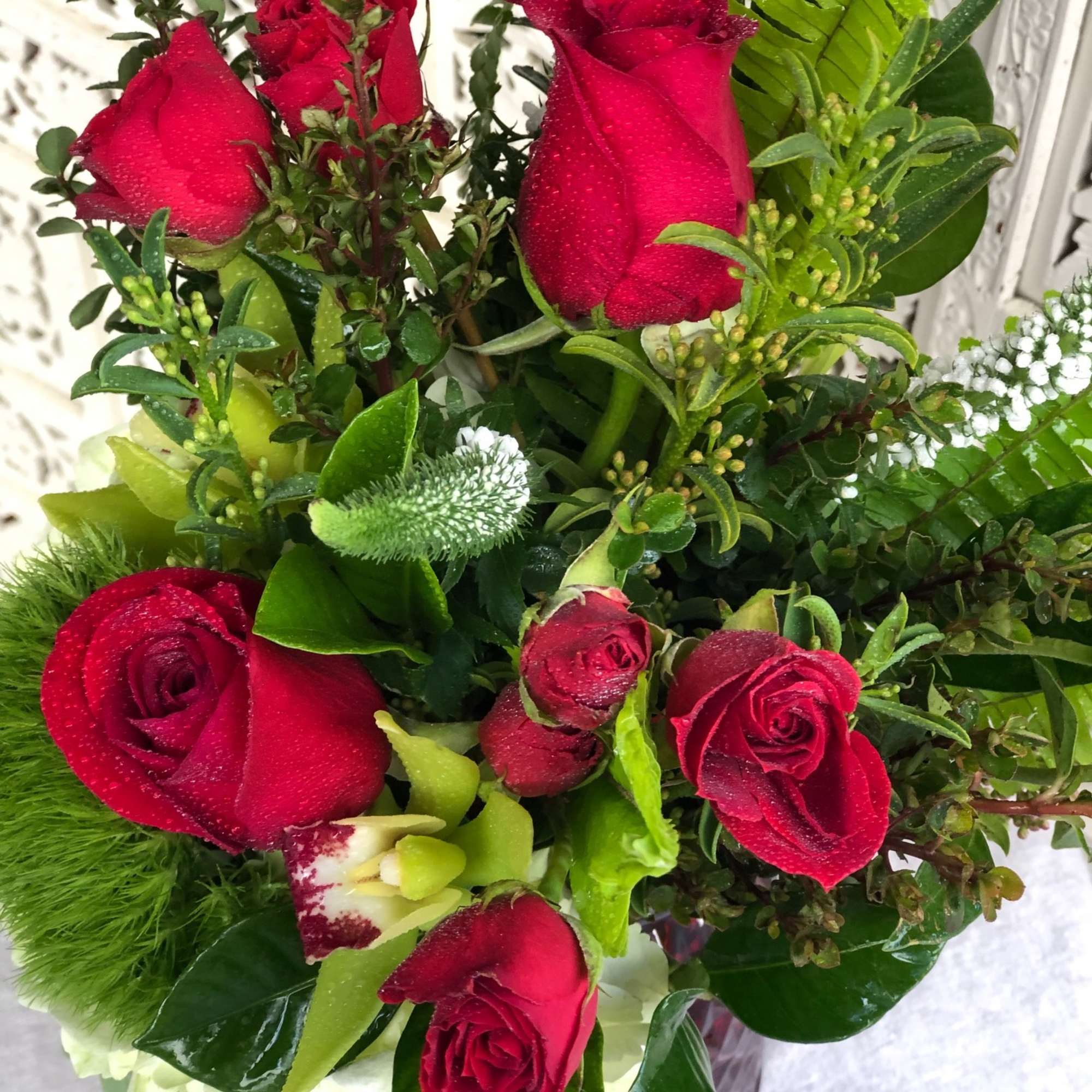 Vibrant red roses and spray roses arranged with delicate, white veronica, luscious