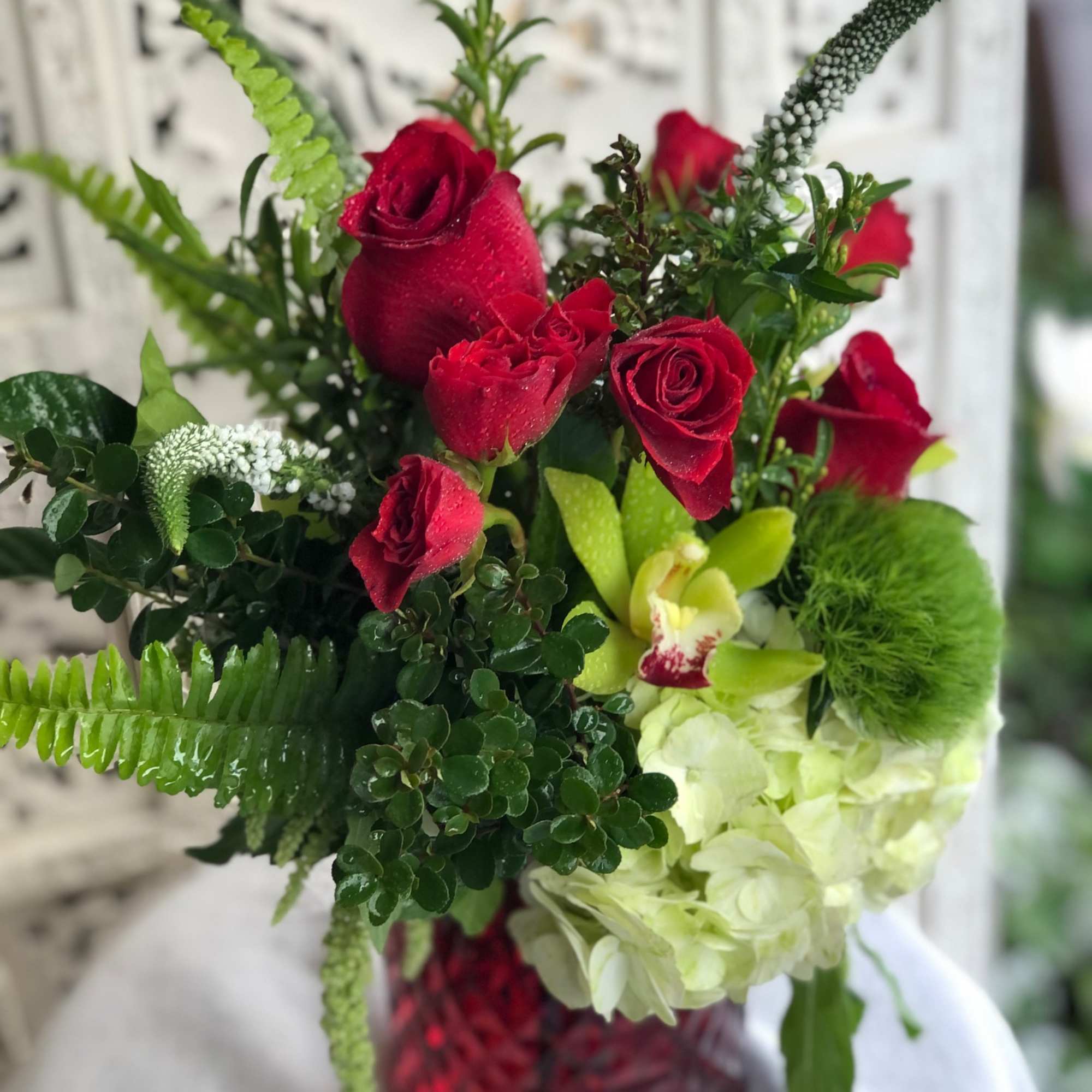 Vibrant red roses and spray roses arranged with delicate, white veronica, luscious