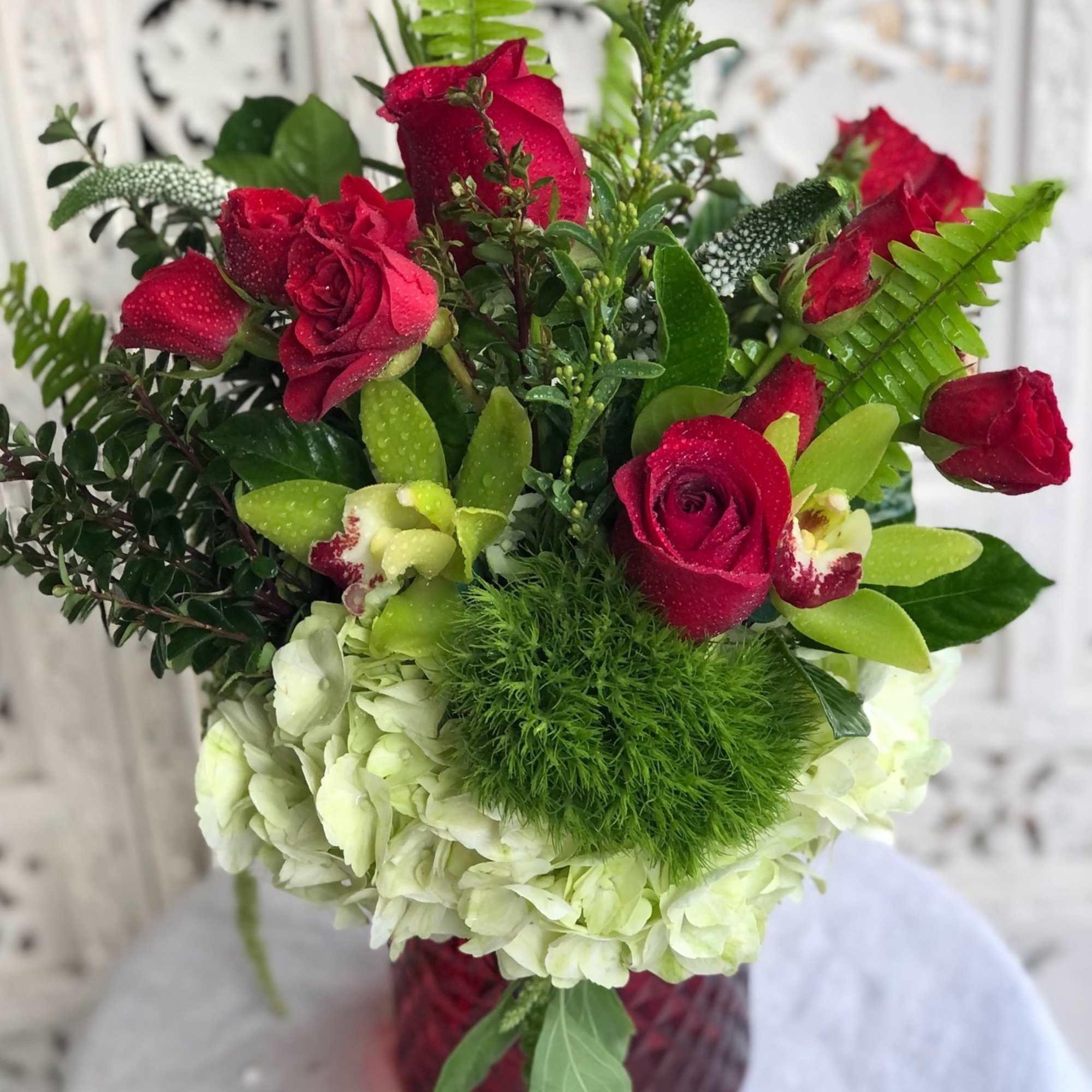 Vibrant red roses and spray roses arranged with delicate, white veronica, luscious