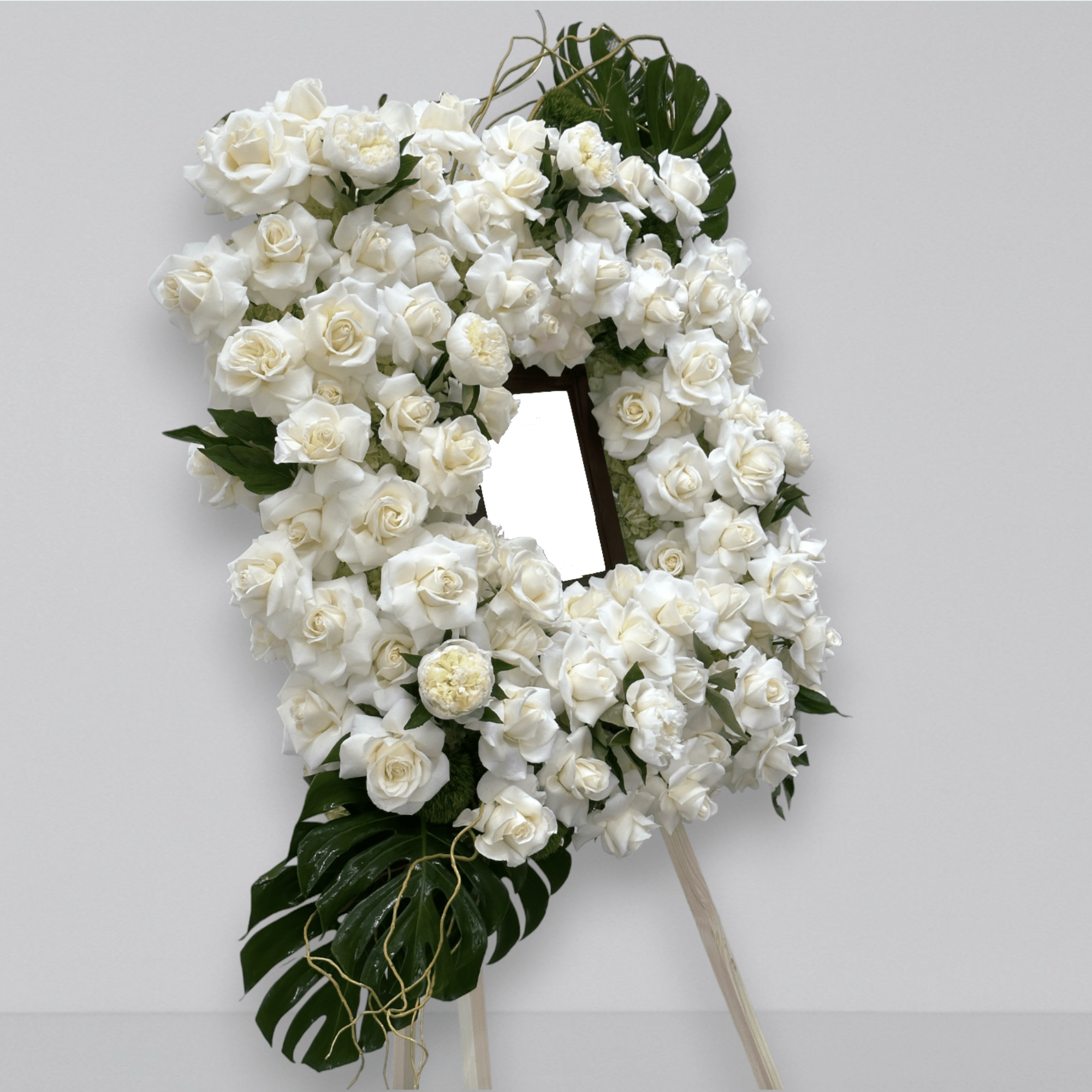 A funeral piece designed as a frame. Filled with fresh florals, roses