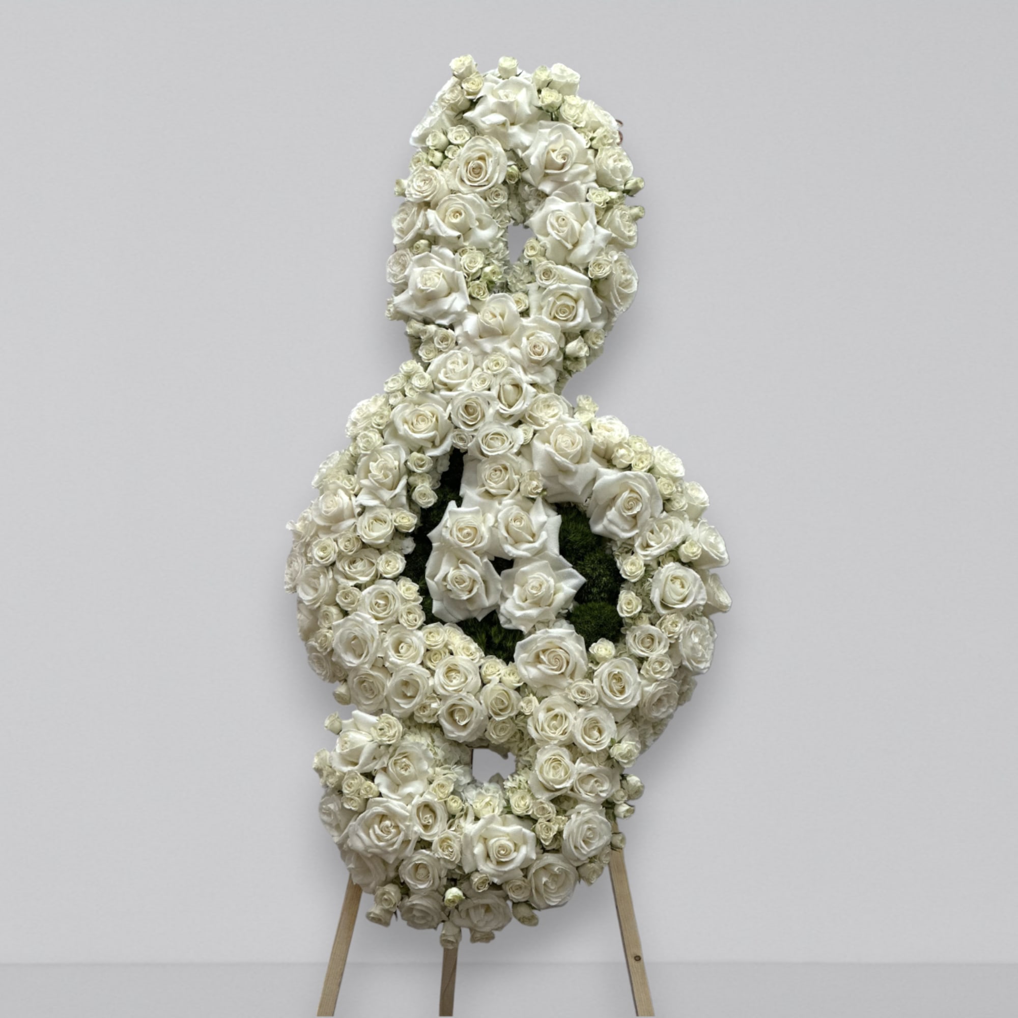 A custom music note funeral arrangement filled with fresh florals; hydrangea, roses