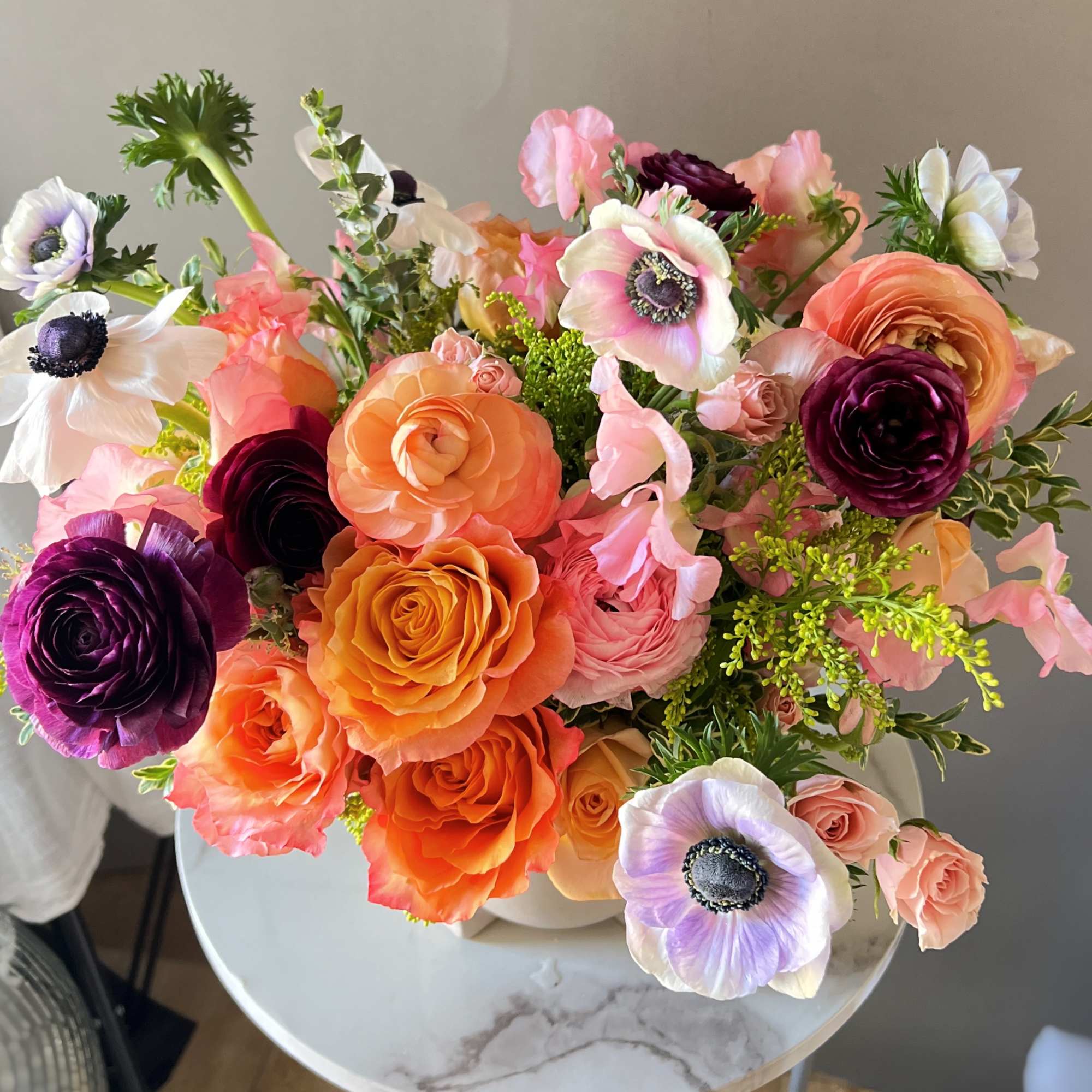 Stunning arrangement with different orange , it has roses,ranunculus,and anemones surrounding it.