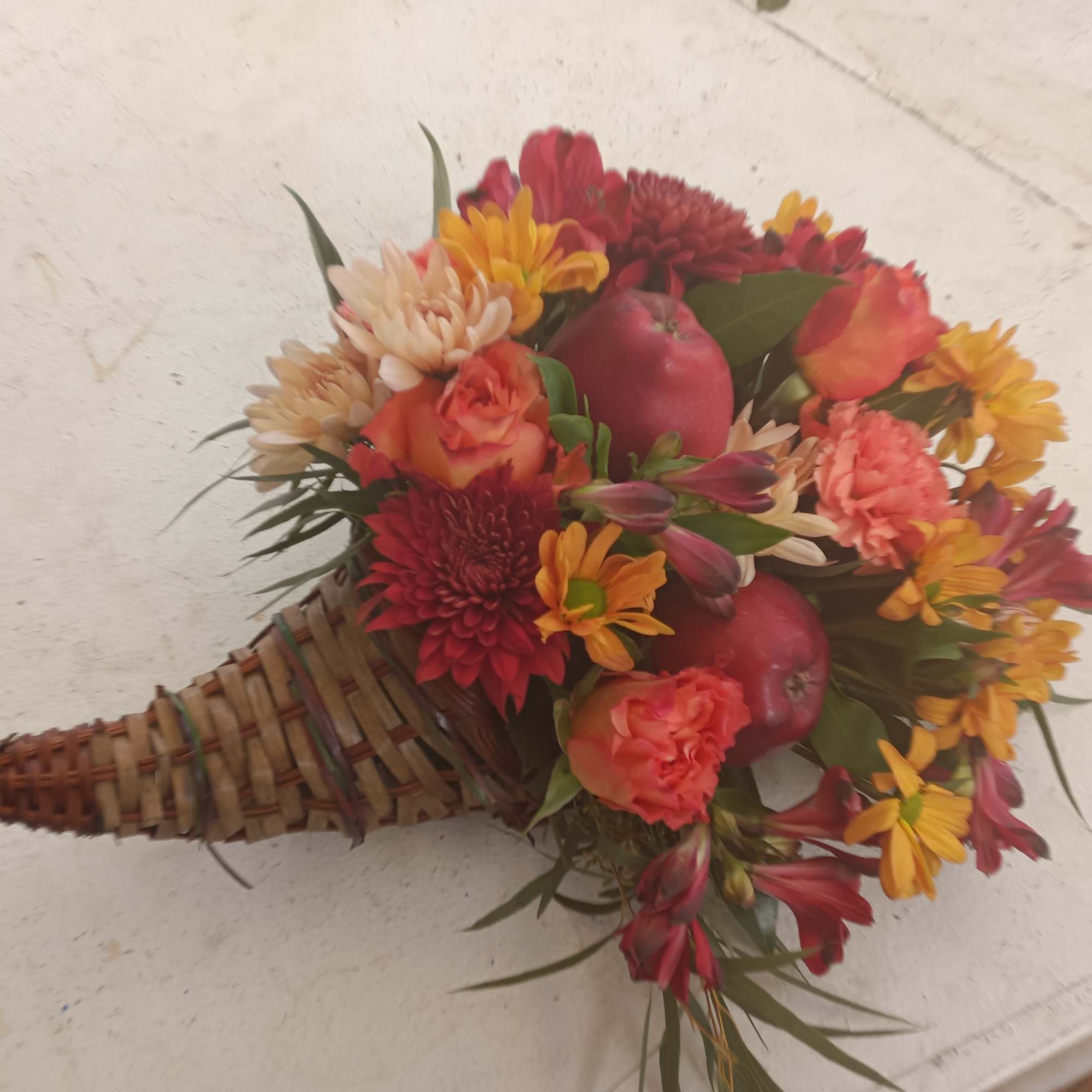 Beautiful rich fall colors roses, daisies, carnations, apples and greens cornucopia centerpiece