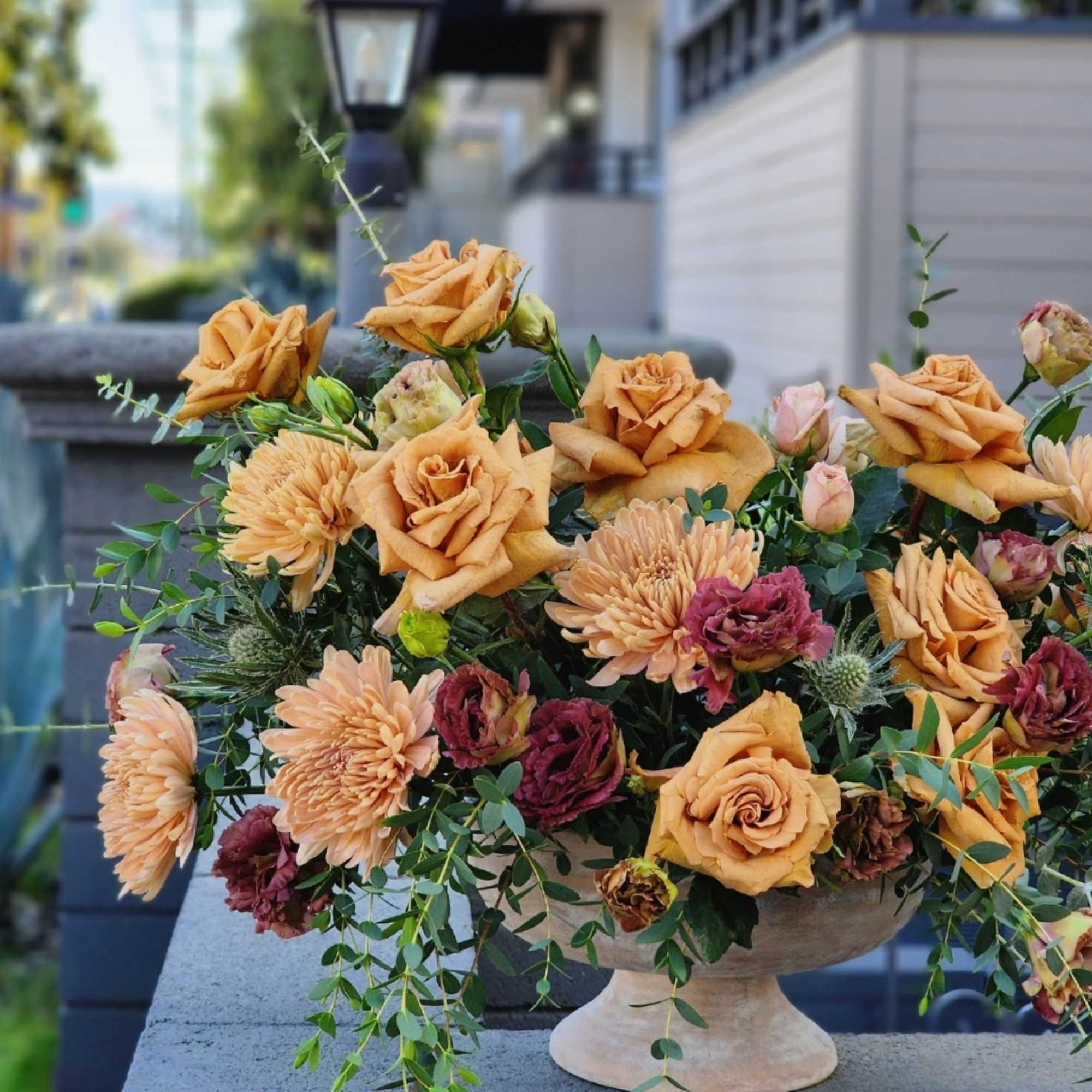 A stunning flower arrangement in a ceramic vase, featuring rich brown caramel