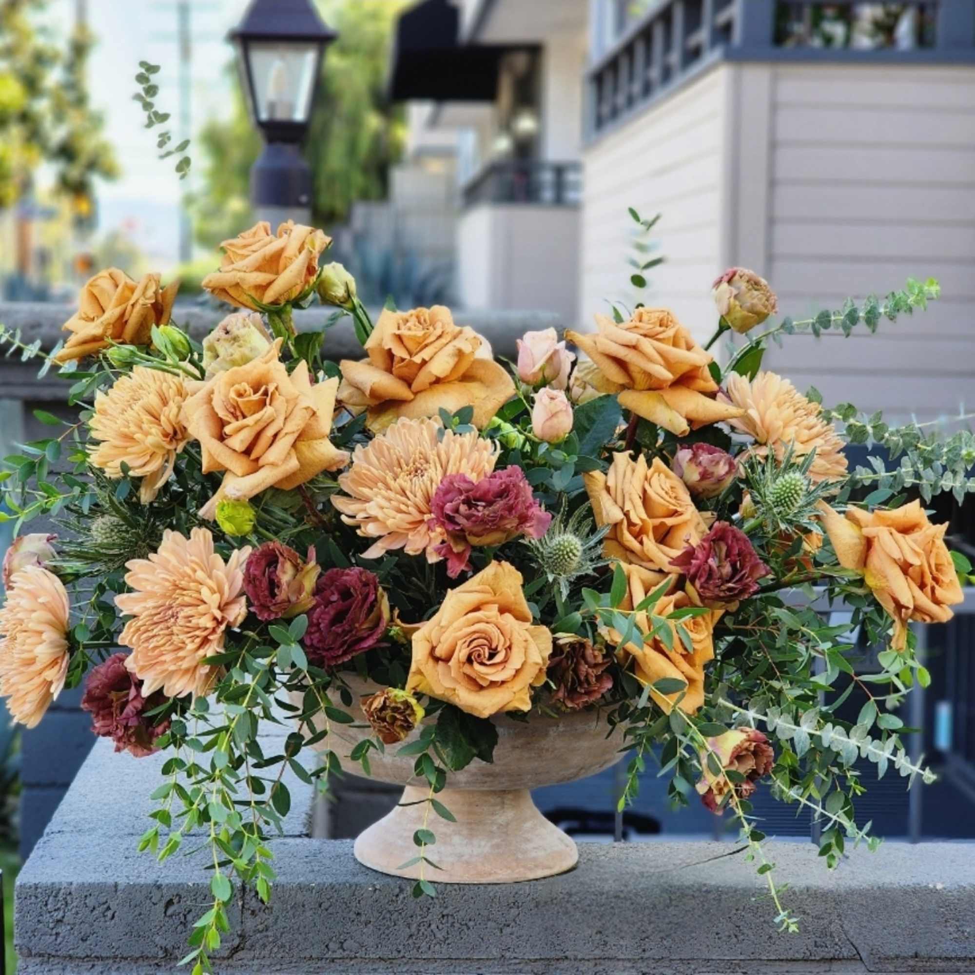 A stunning flower arrangement in a ceramic vase, featuring rich brown caramel