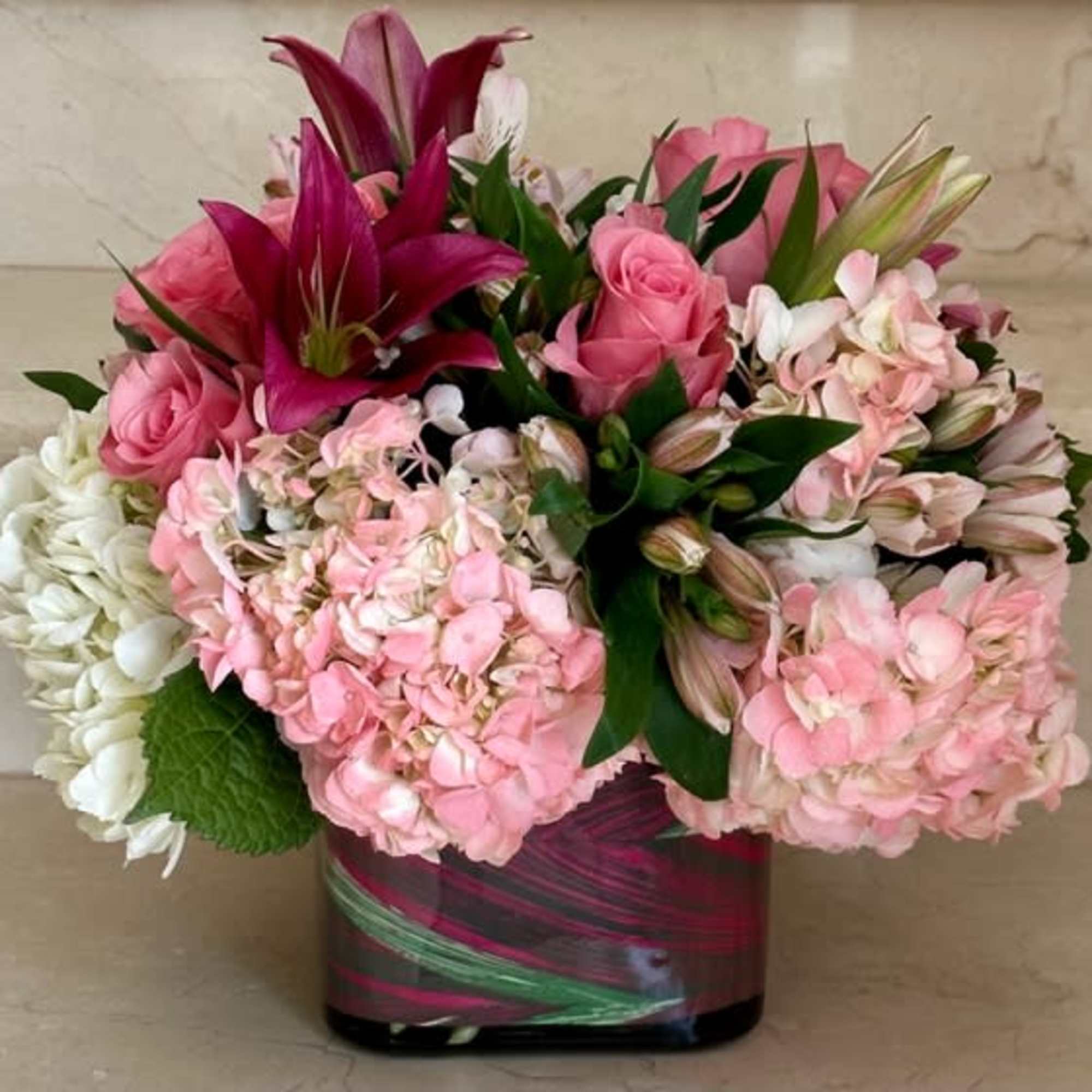 Hydrangeas, Roses, Lilies and accent flowers arranged round in a vase