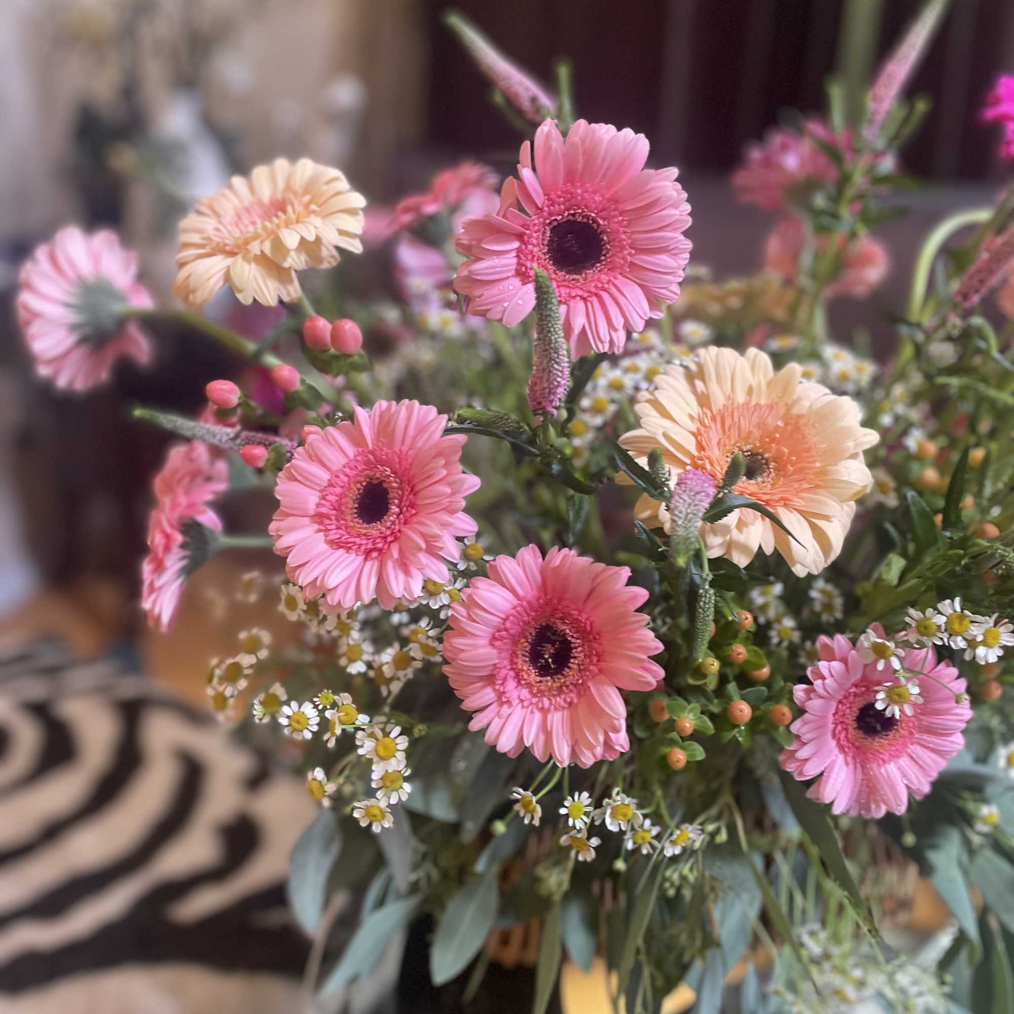 Nestled in a charming picnic basket, a vibrant flower arrangement awaits, adorned