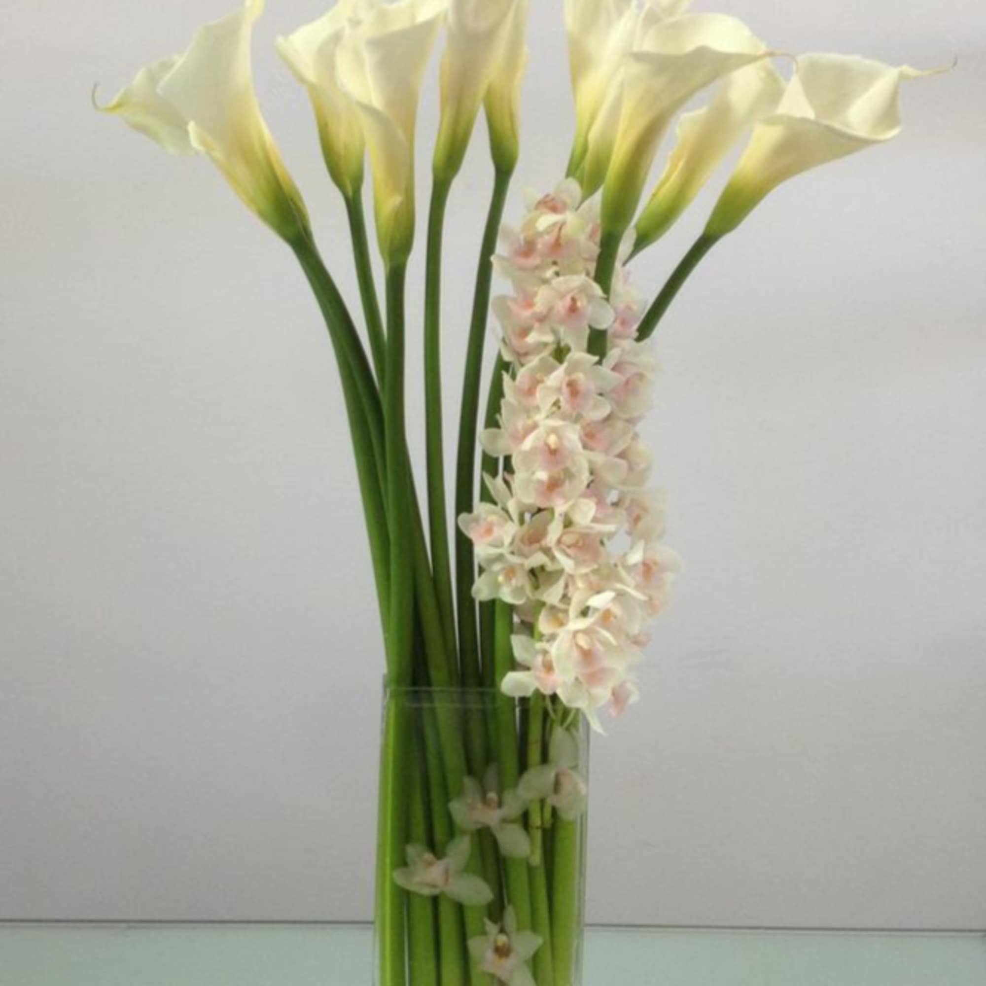 Calla lilies and orchids combine to create a tall and striking piece