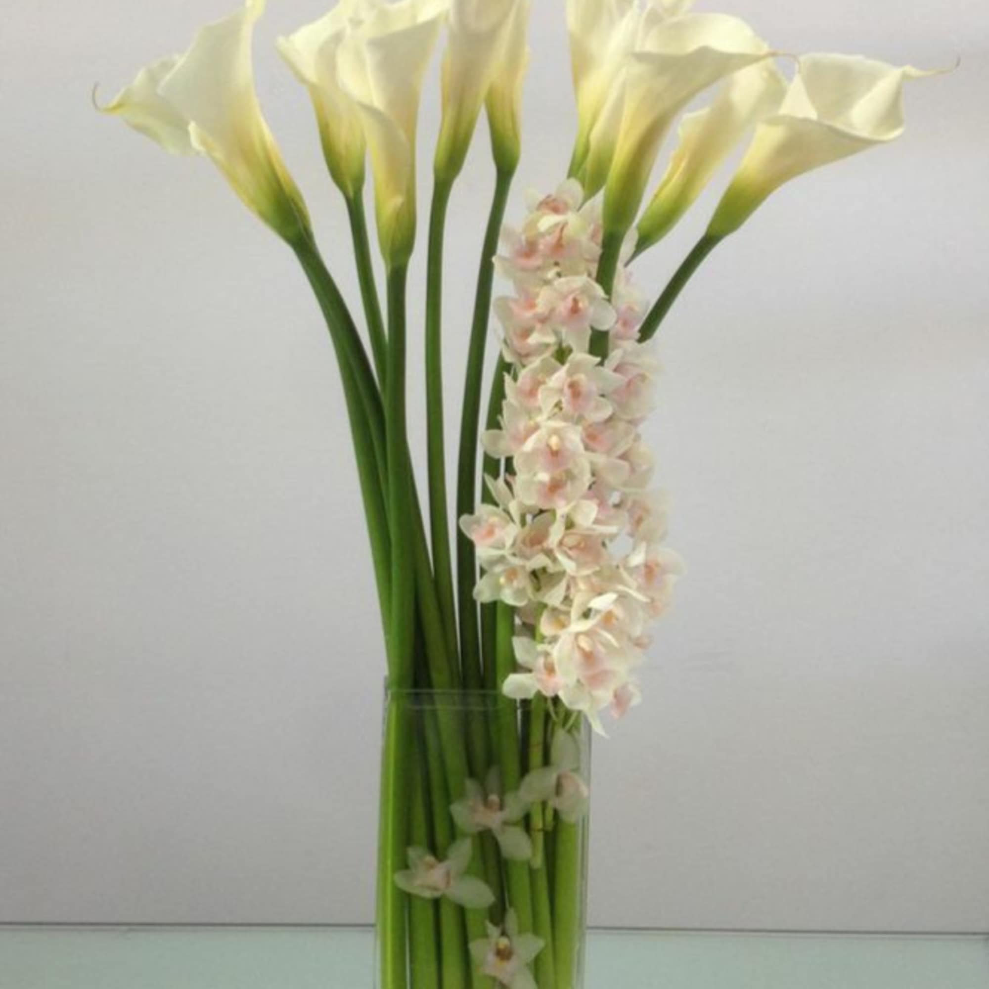 Calla lilies and orchids combine to create a tall and striking piece
