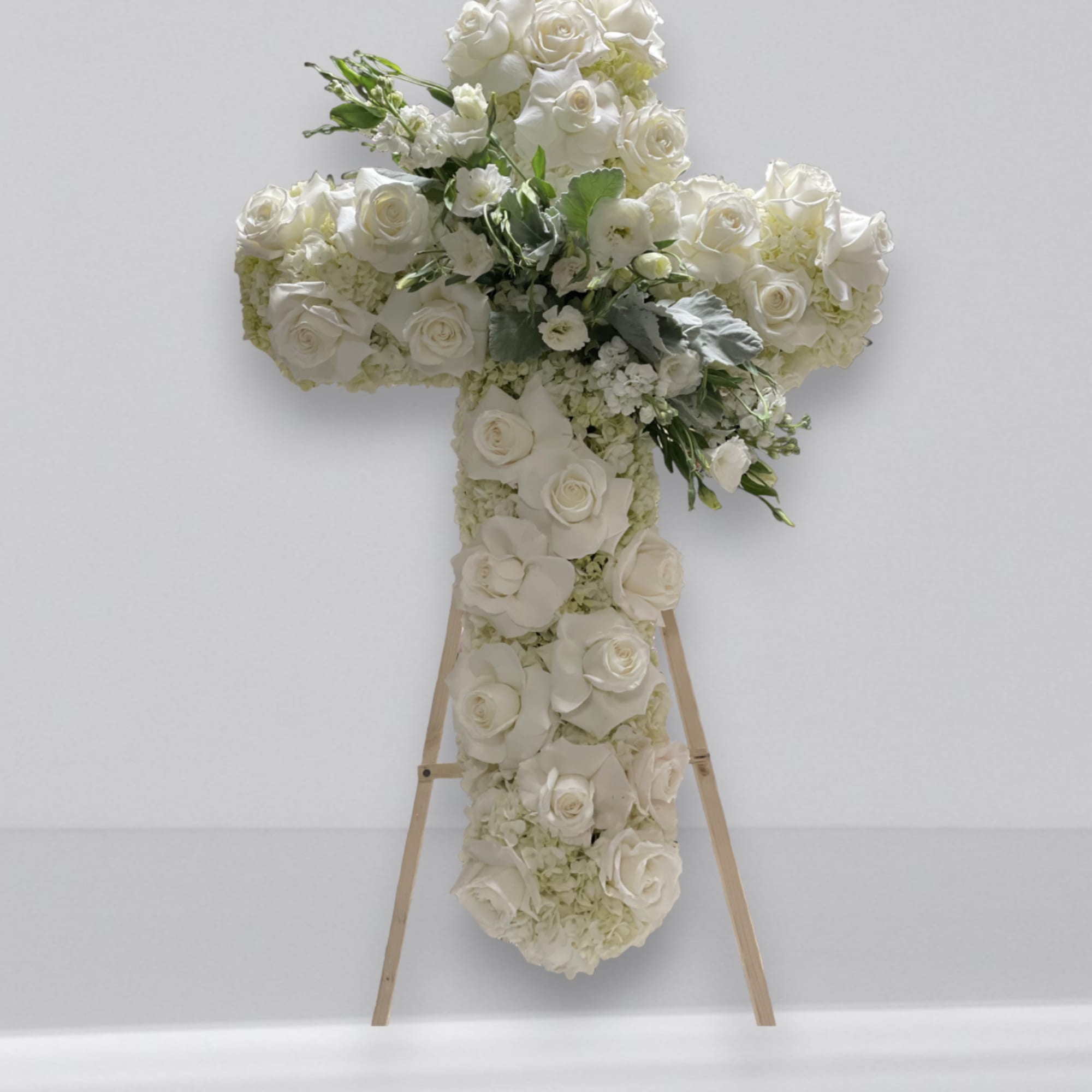 Elegant white funeral cross arrangement. Designed with a mix of roses, spray