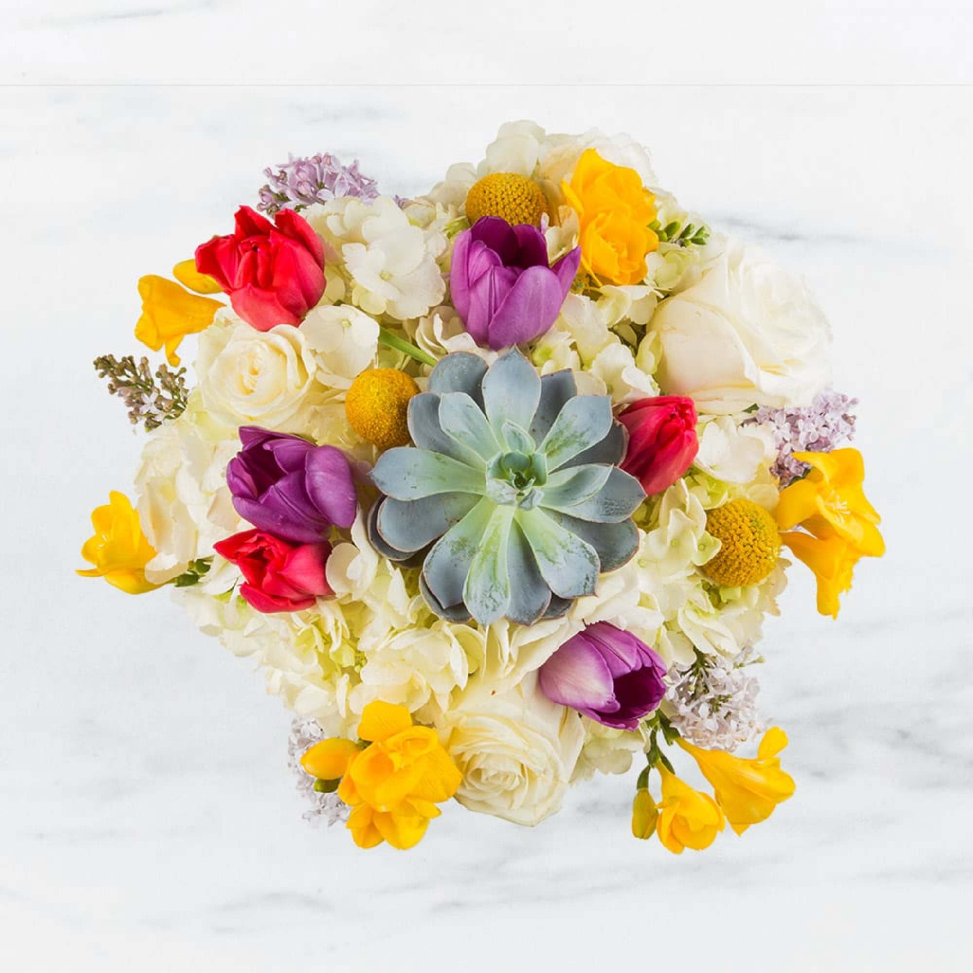 This arrangement includes hydrangea, tulips, freesia, succulents and other seasonal blooms. This