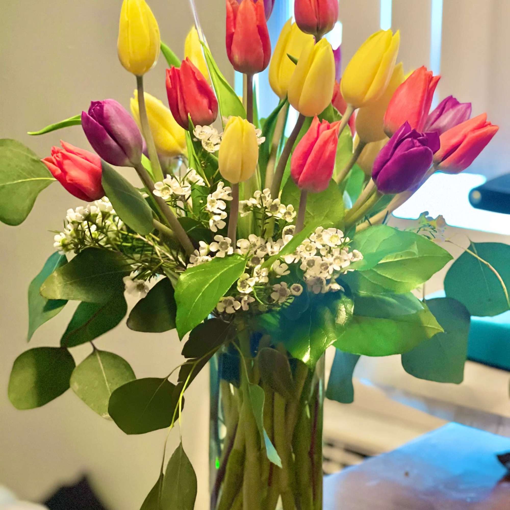 A colorful mixture of 20 Tulips accented by wax flower in a