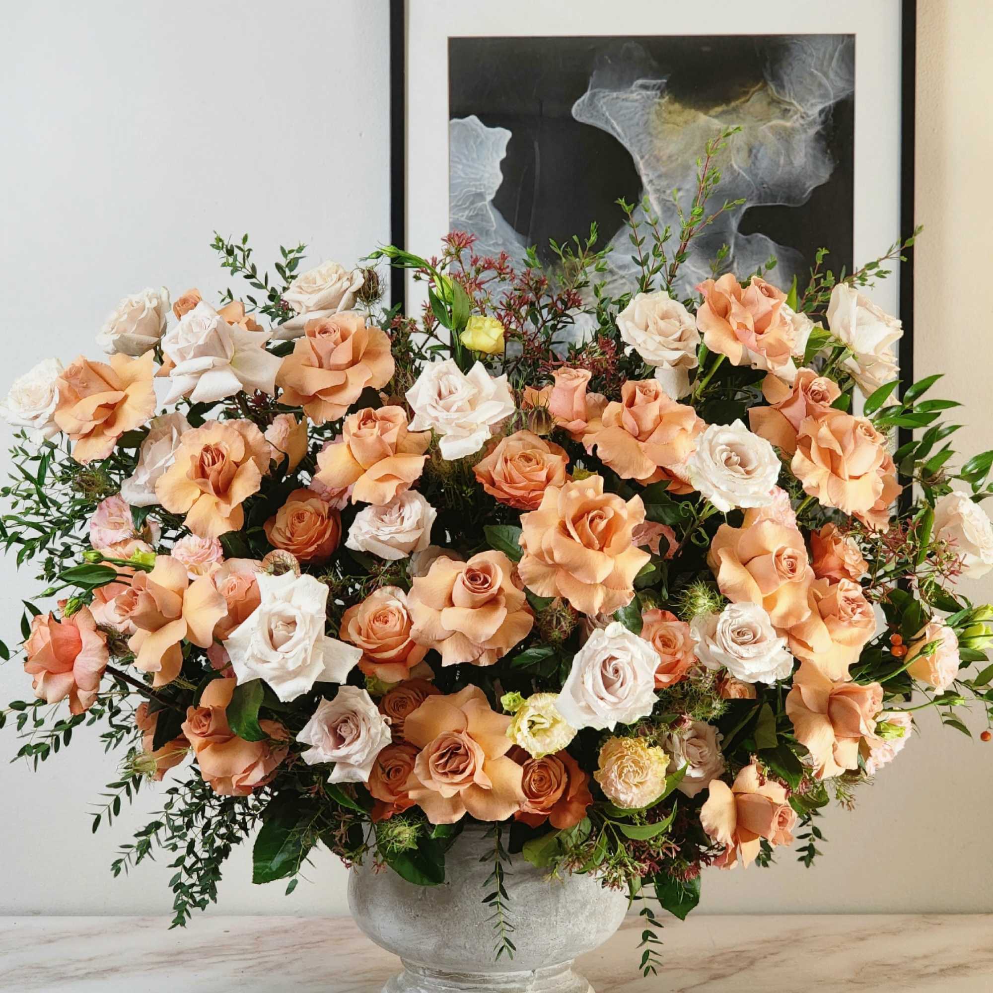 A grandiose vase holds an enchanting blend of beige and peach roses