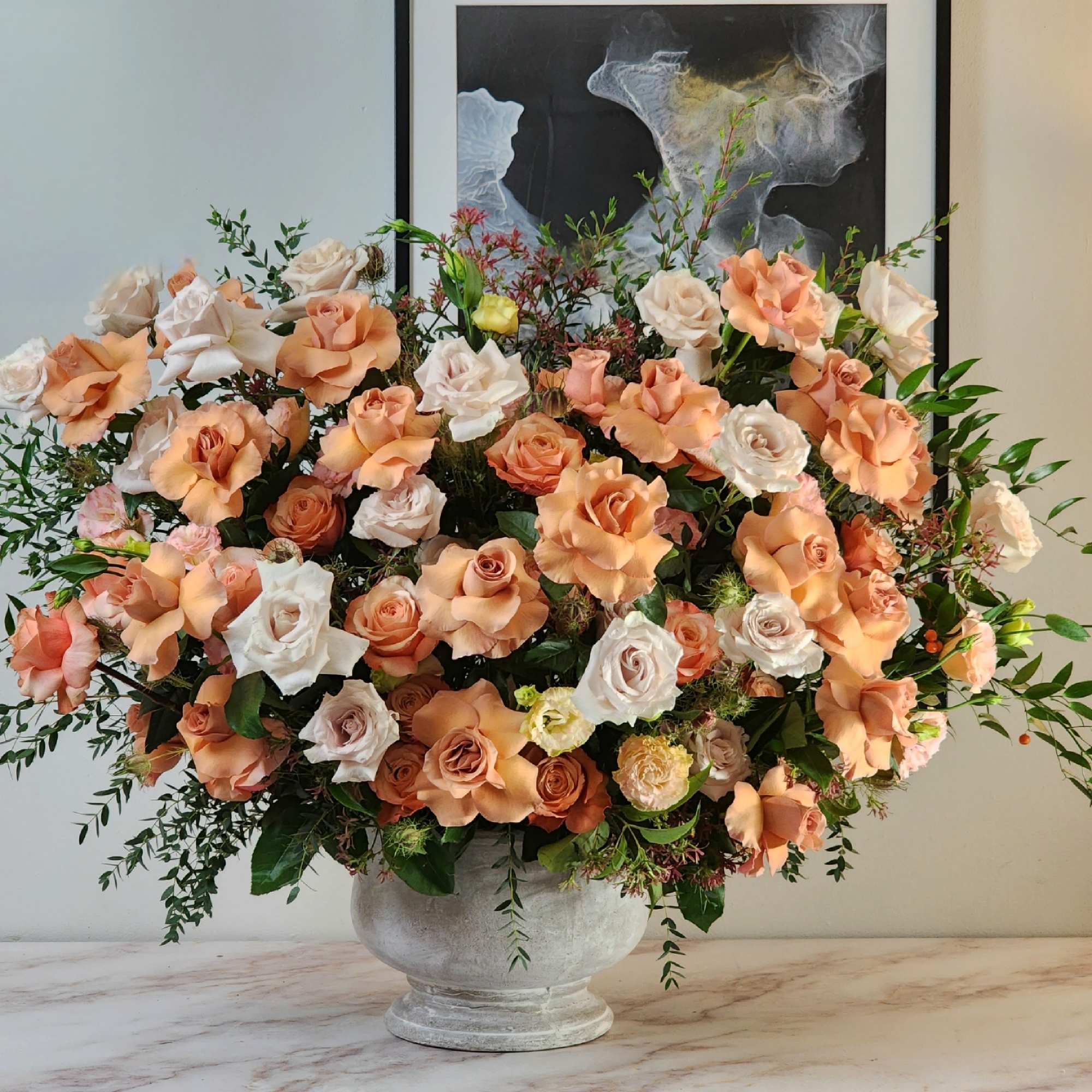 A grandiose vase holds an enchanting blend of beige and peach roses