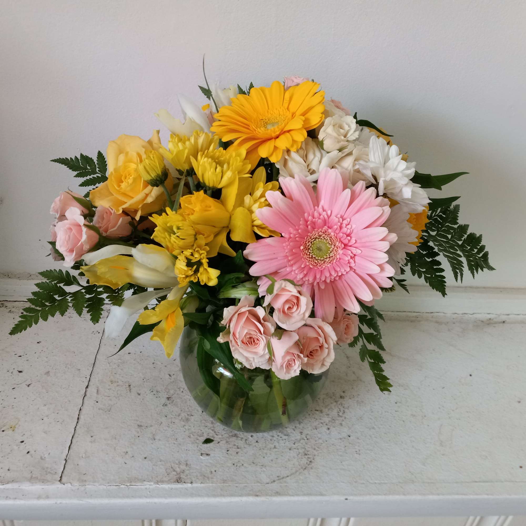 Beautifully lined pink/yellow mix of roses and spring flowers in a vase