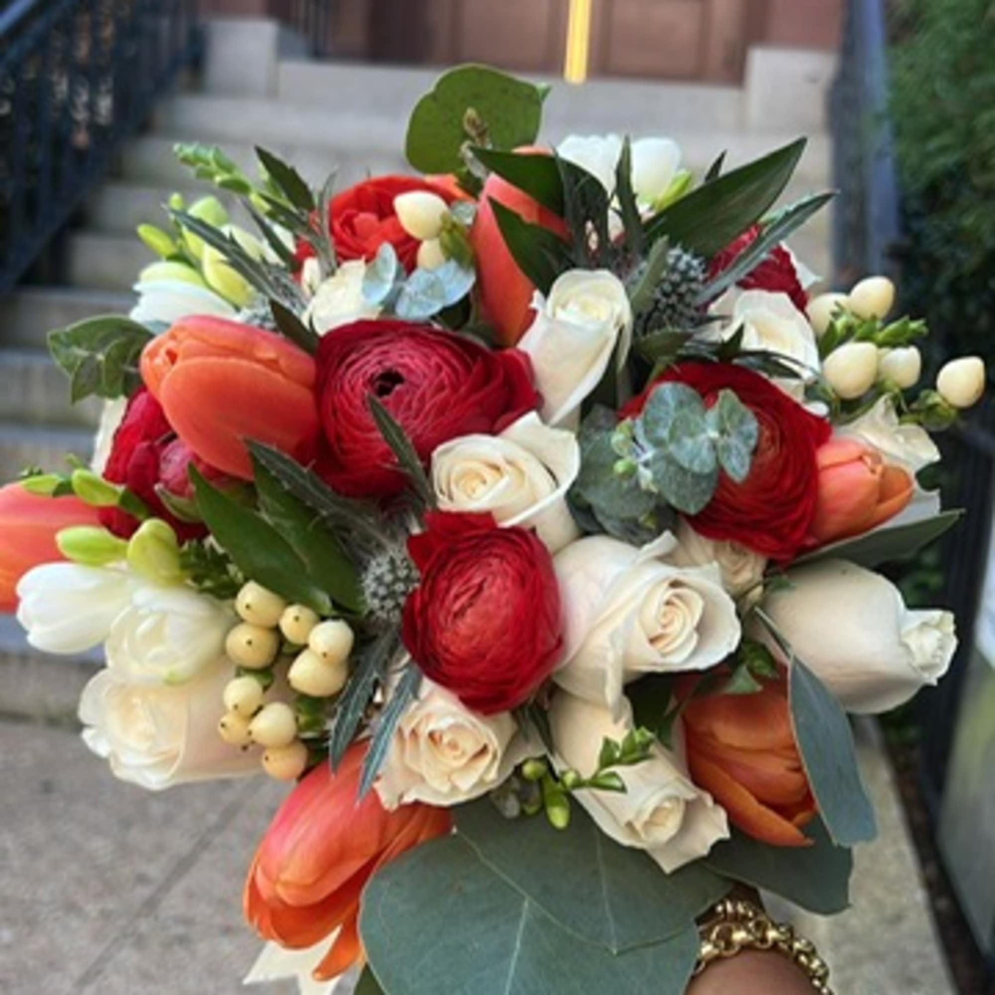 A classic bridal bouquet of roses and tulips hand-tied with ribbon with