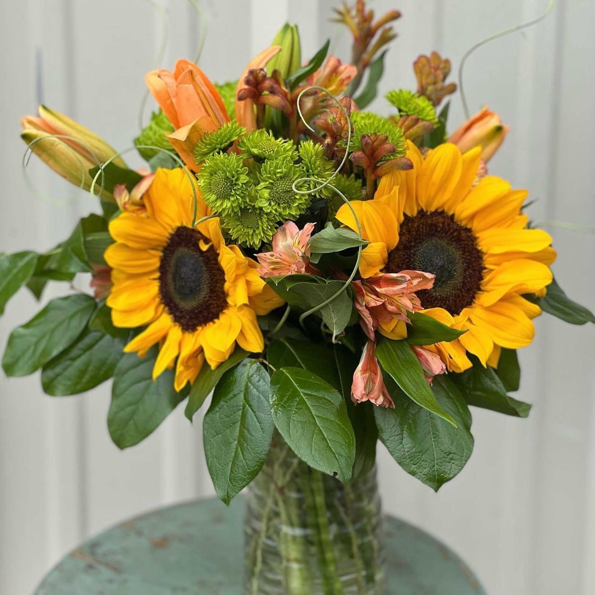 Designers Choice of Fall tones of fresh cut florals in Clear Vase