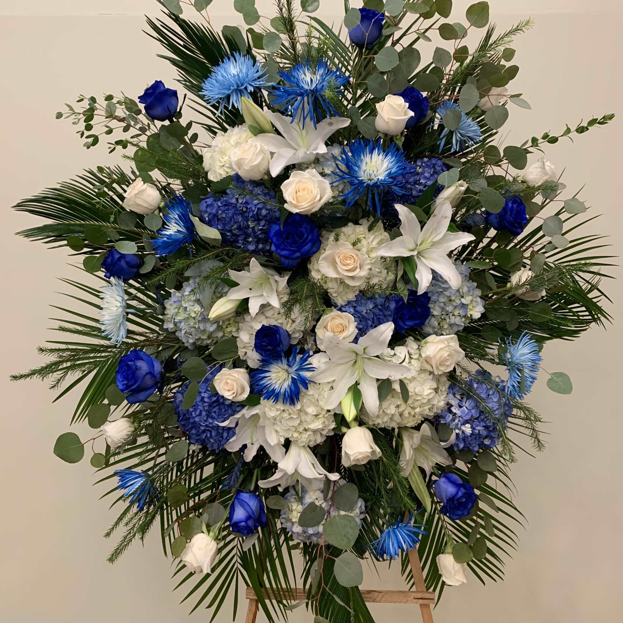 Extraordinarily  standing spray designed with all different shapes of blue flowers