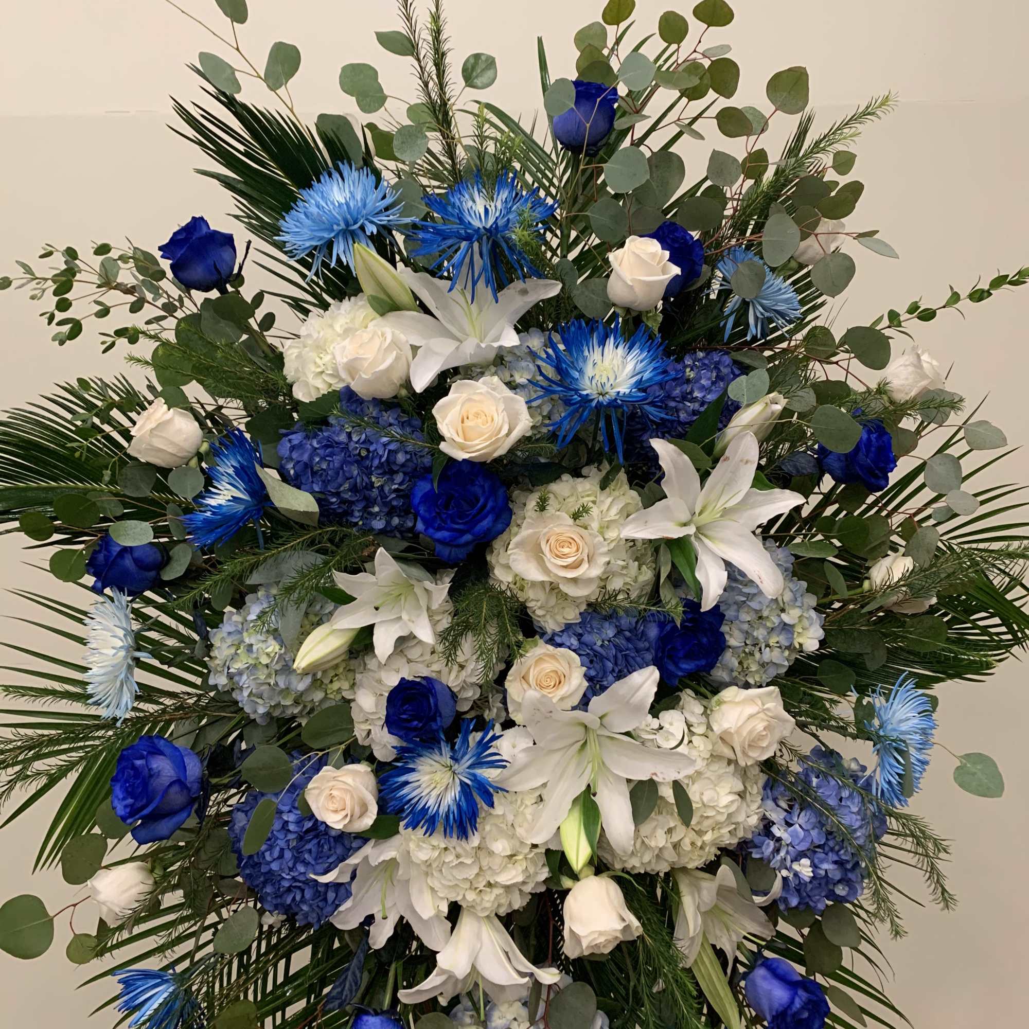 Extraordinarily  standing spray designed with all different shapes of blue flowers