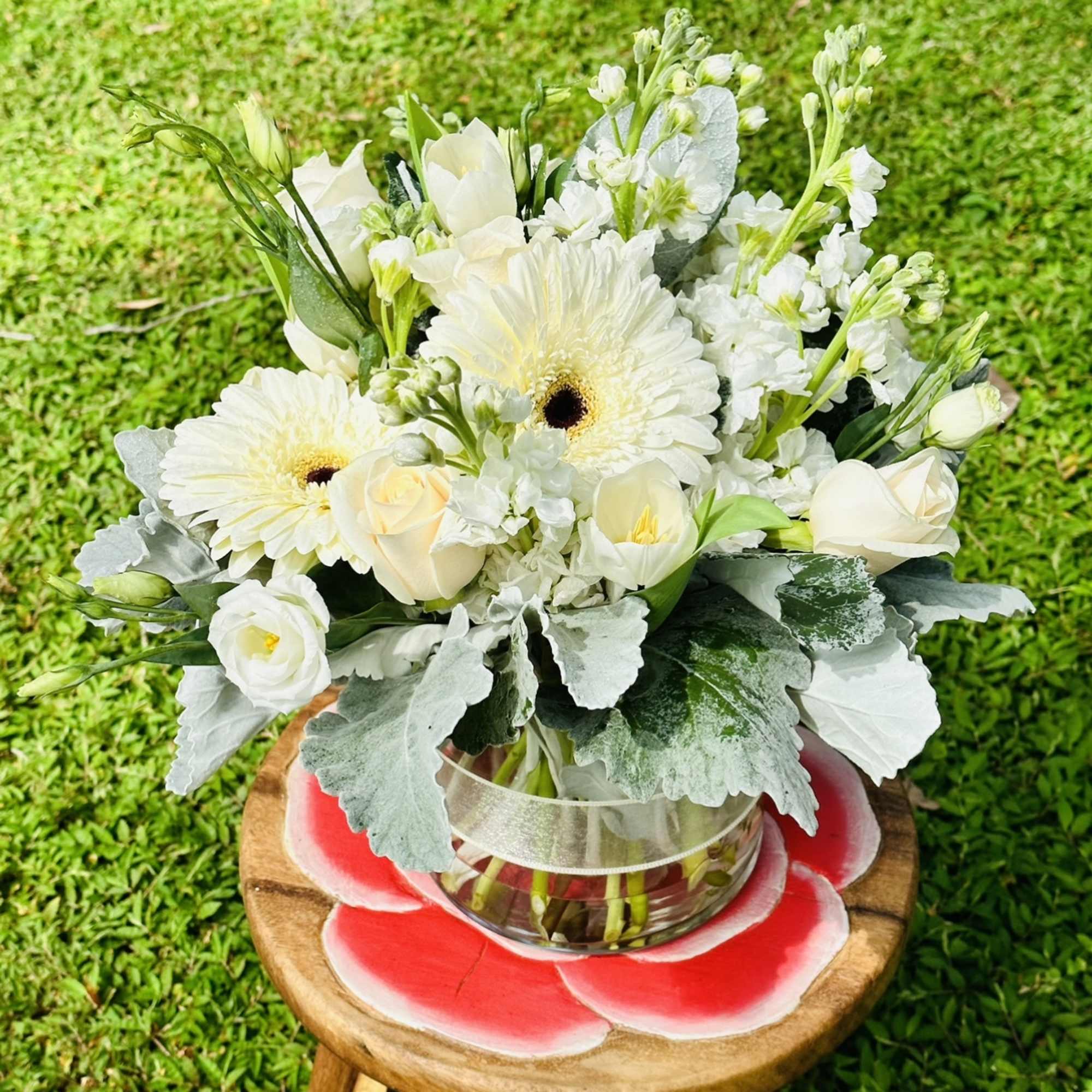 This arrangement contains gerbera daisies, roses, tulips, stock, and other seasonal blooms.