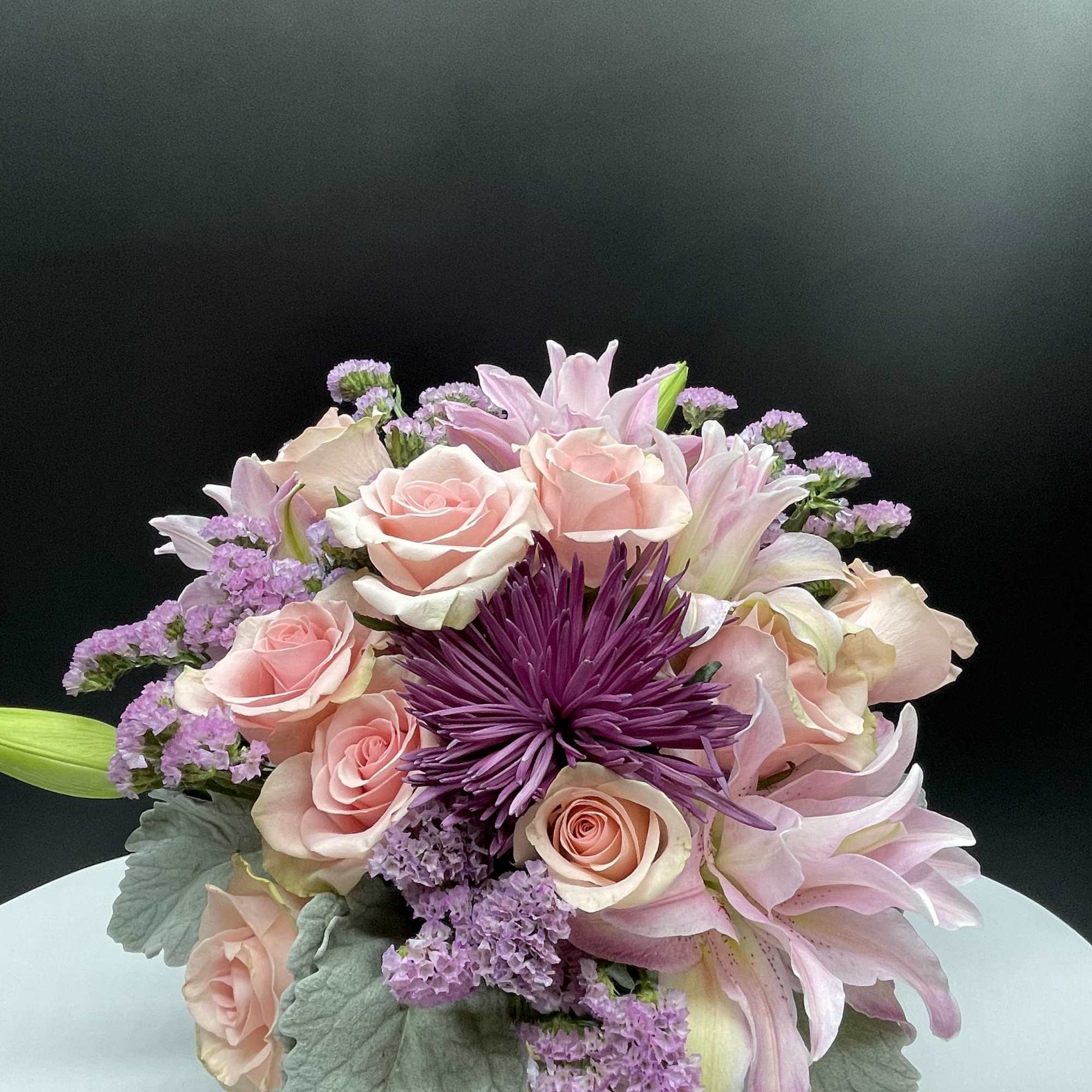 A combination of pink roses,moms, rose lilies &amp; dusty miller in rose