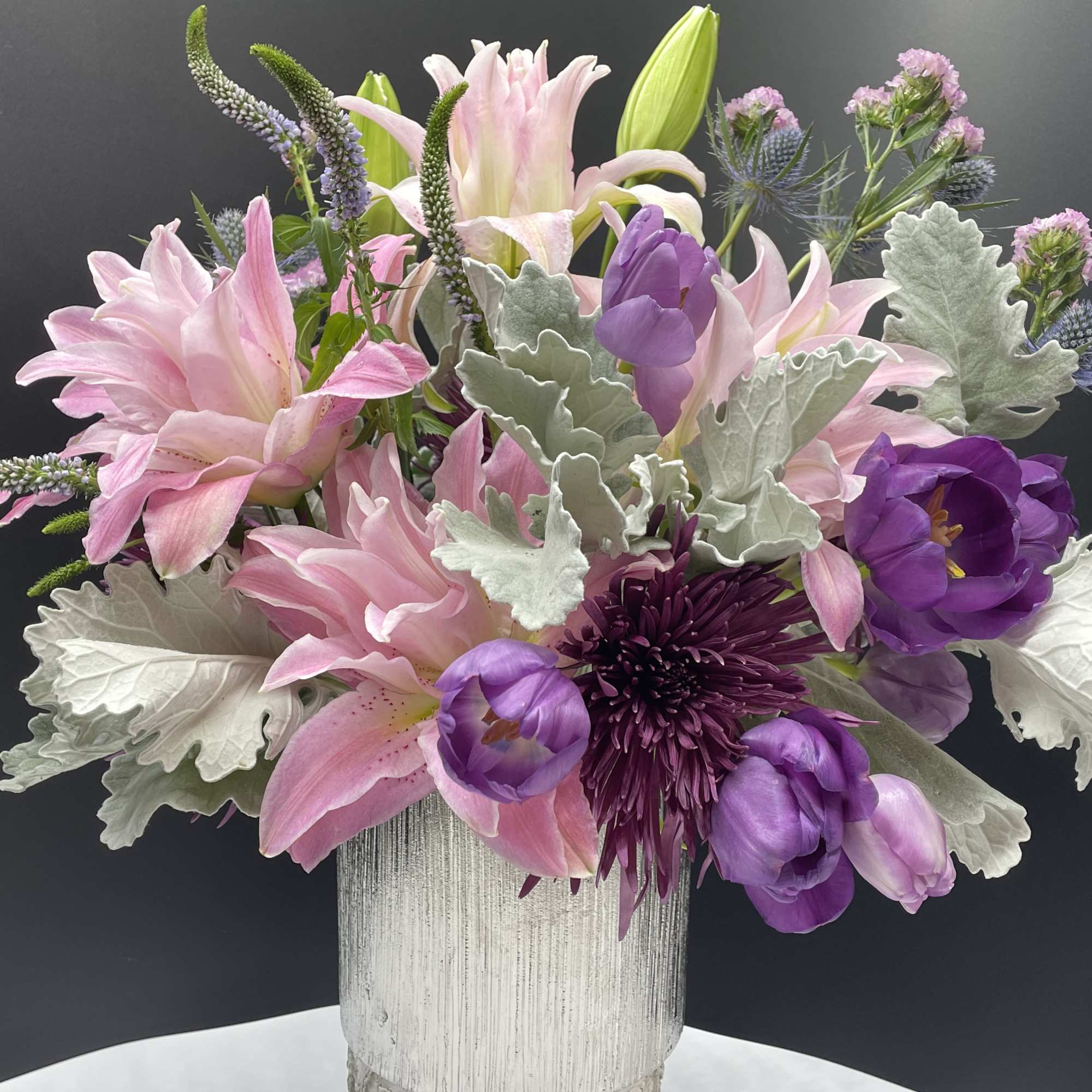 A combination of pink roses,moms, rose lilies &amp; dusty miller in rose