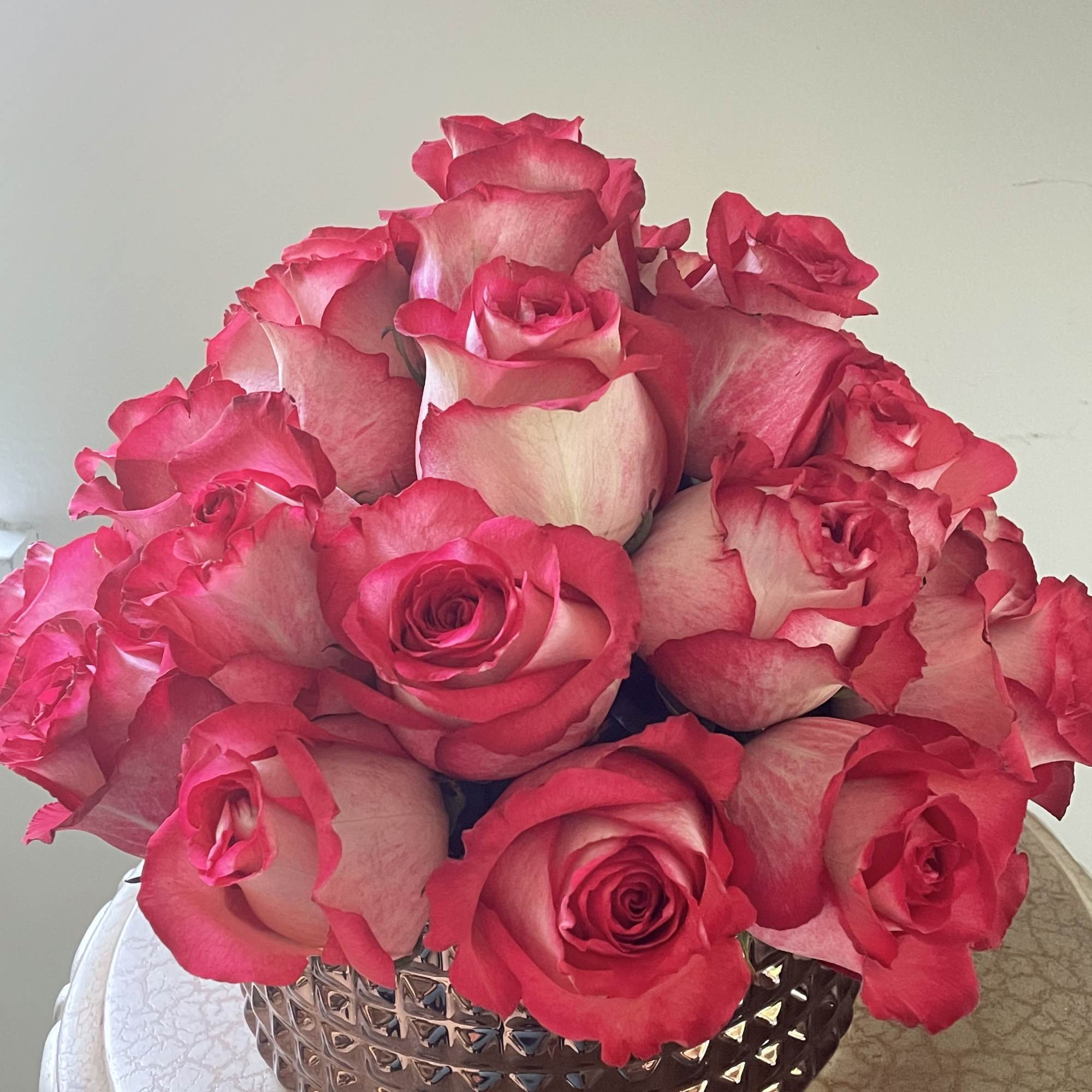 Two dozen extra large roses in a dark rose gold ceramic vase.