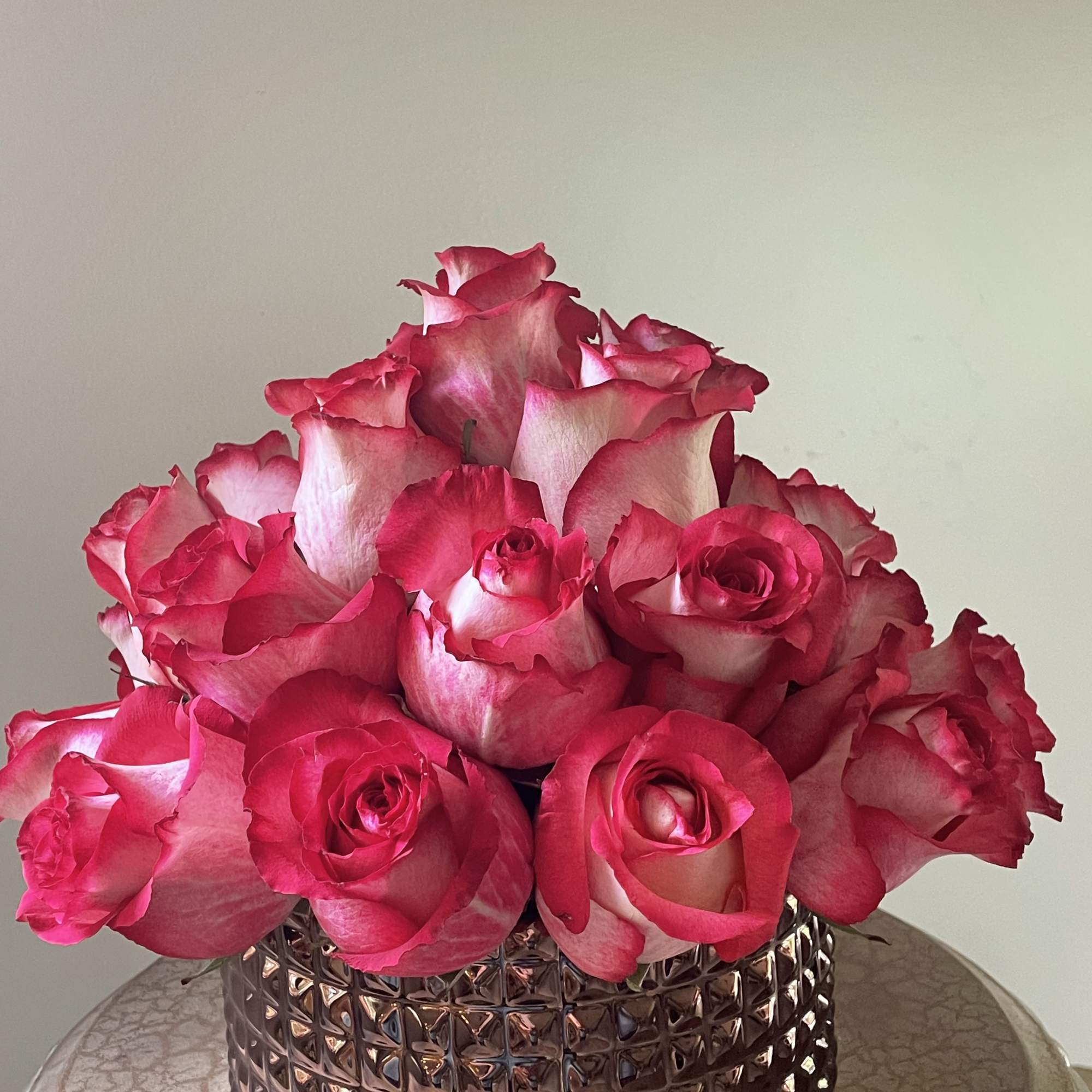 Two dozen extra large roses in a dark rose gold ceramic vase.