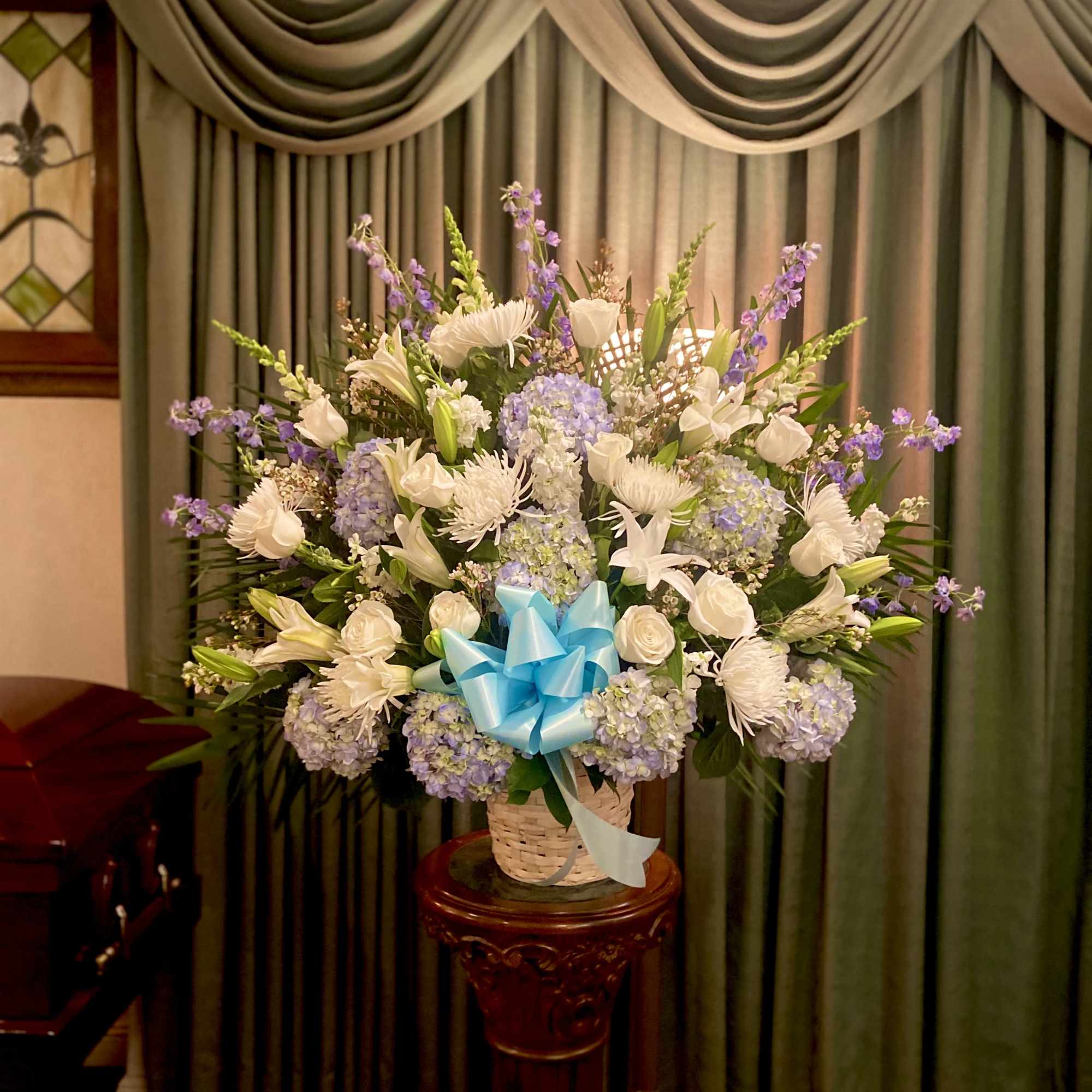 This beautiful white and blue flower basket includes Hydrangeas, Roses, Delphinium and