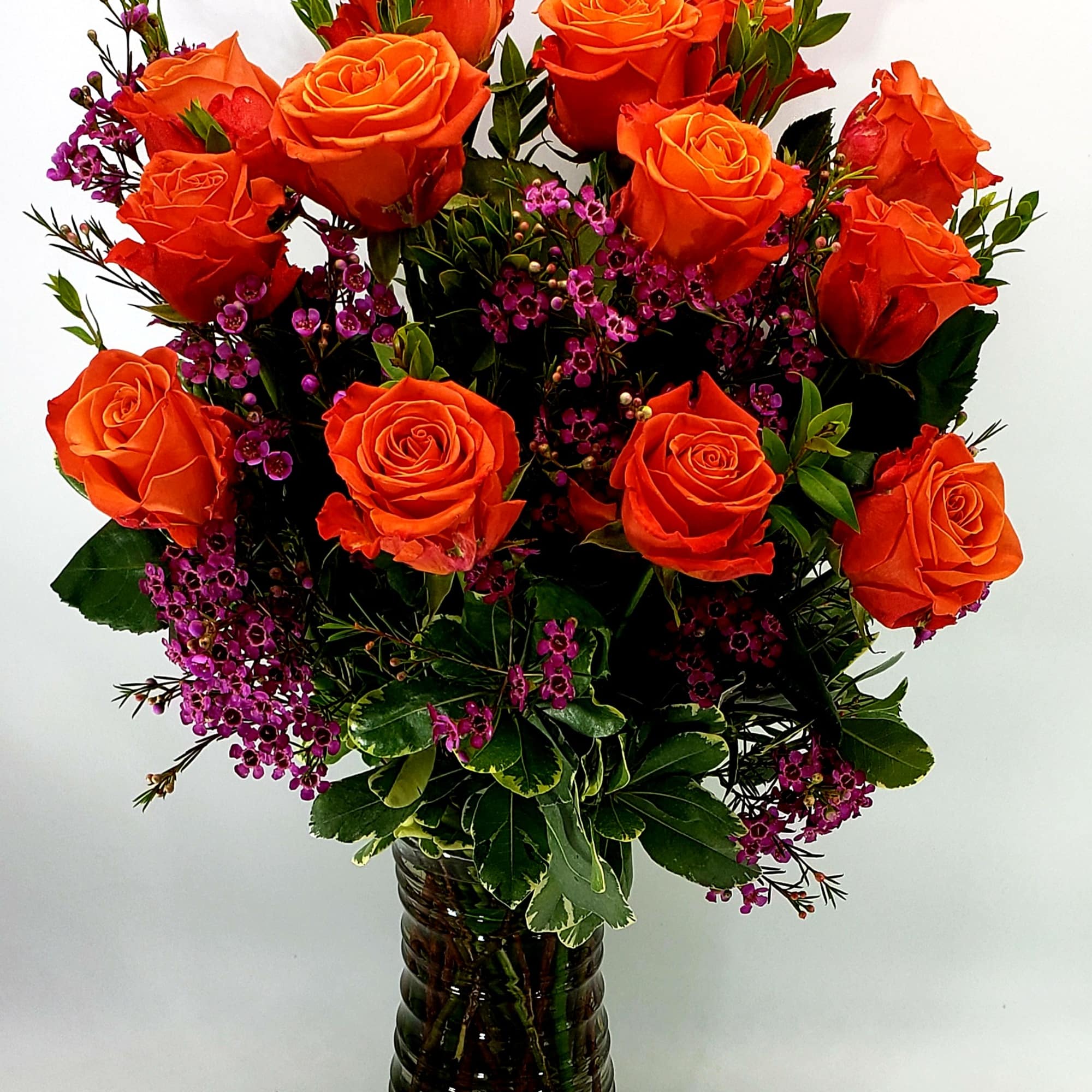 Orange Roses arranged in a clear glass vase.