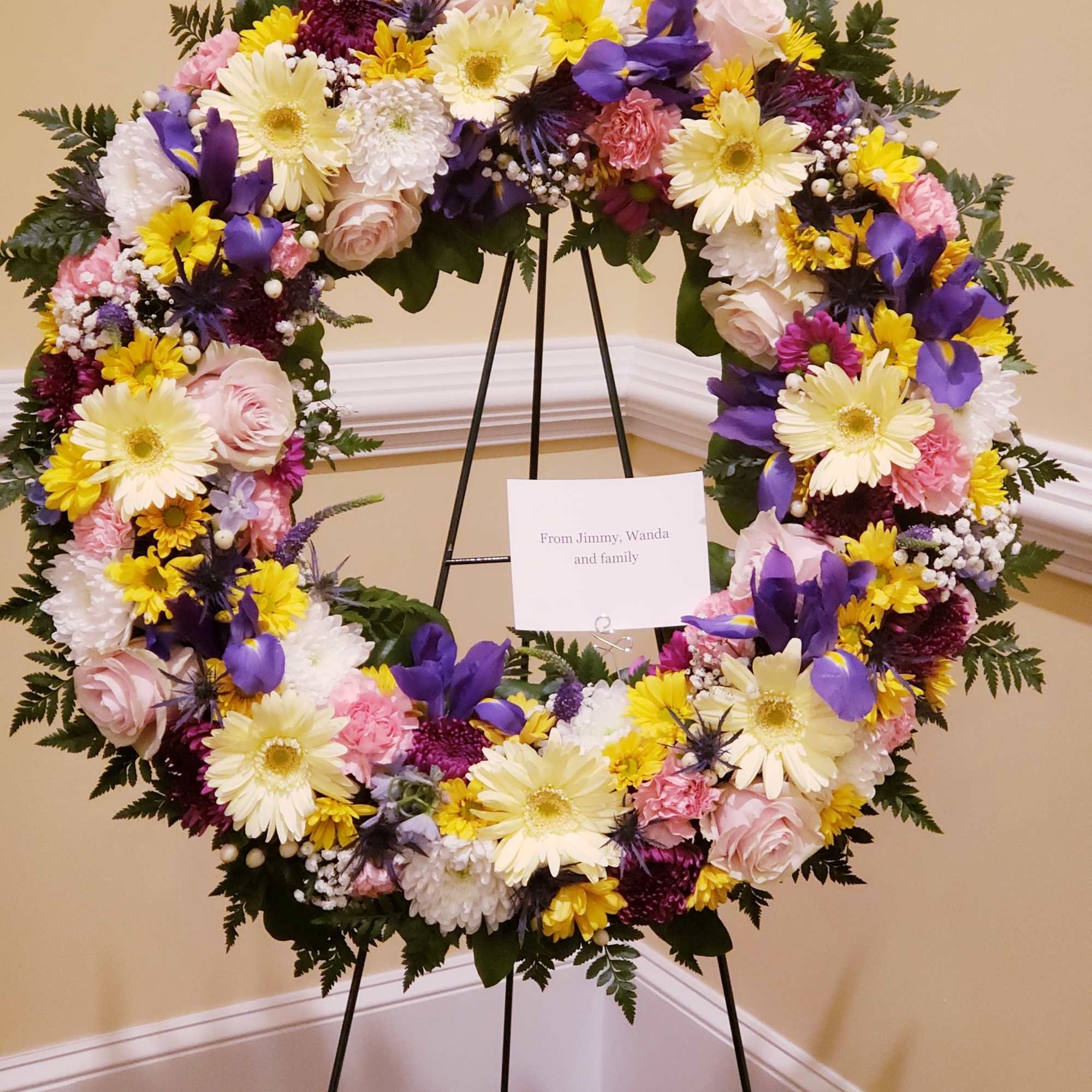 A bright standing wreath of greenery and fresh flowers in yellow, pink A bright standing wreath of greenery and fresh flowers in yellow, pink