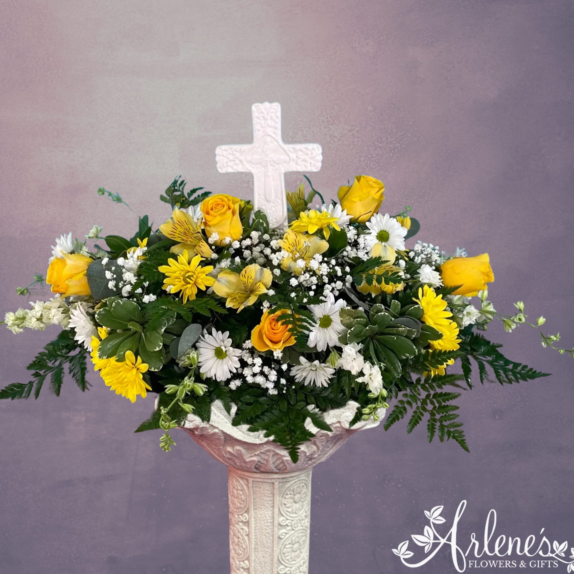 A ceramic cross rises from a field of roses and daisies.  A ceramic cross rises from a field of roses and daisies.