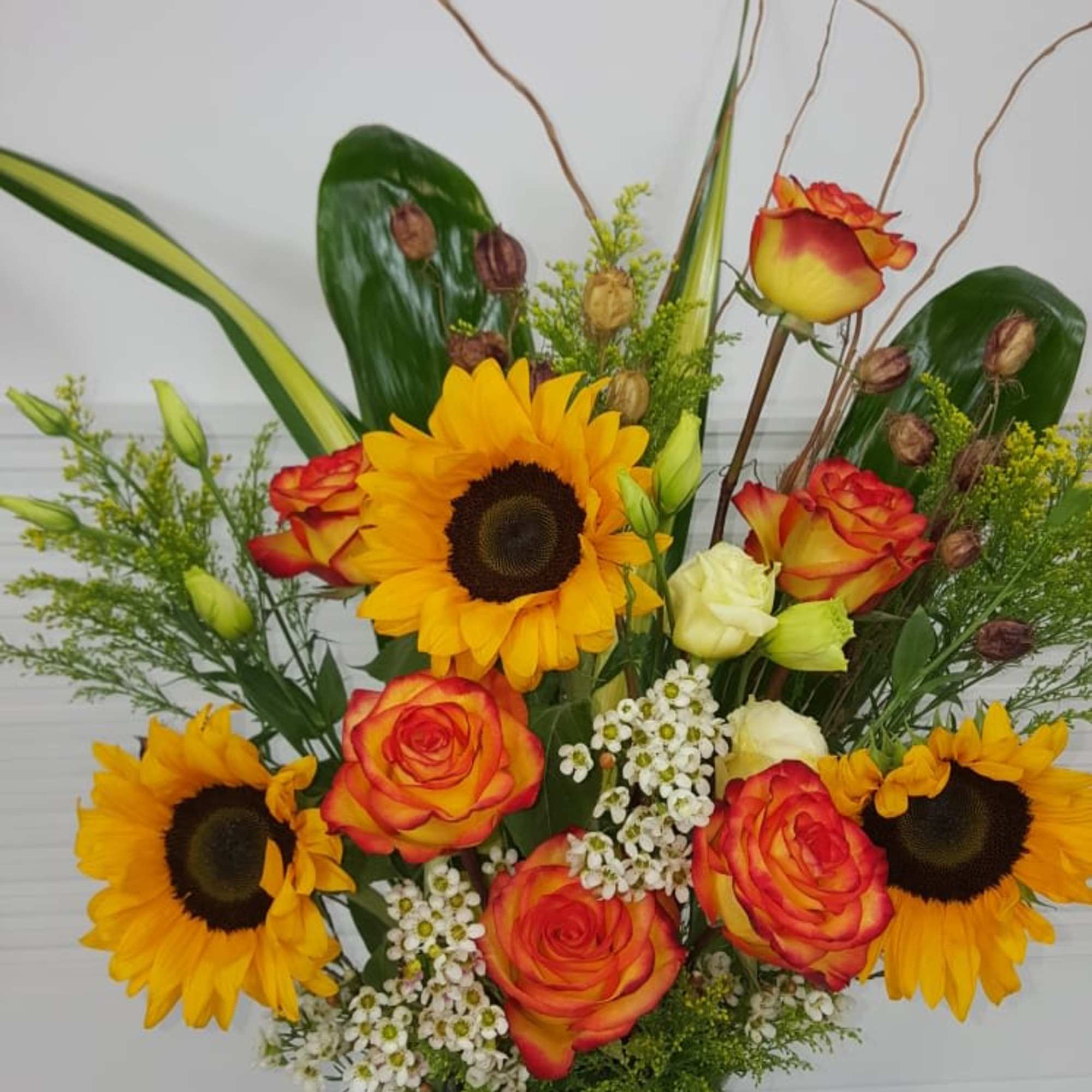 Antique pottery vase filled with large Sunflowers, Roses, Lisianthus, and variety of