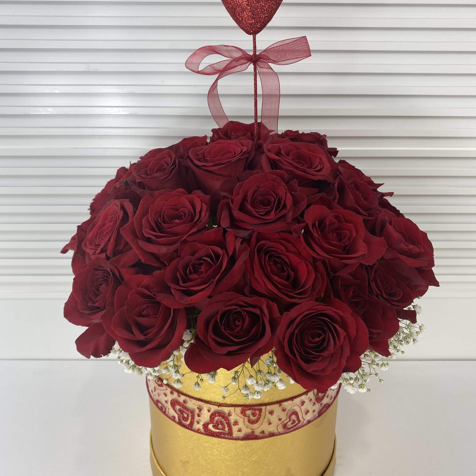 Golden round box with 38-40 red roses surrounded with white baby breath.
