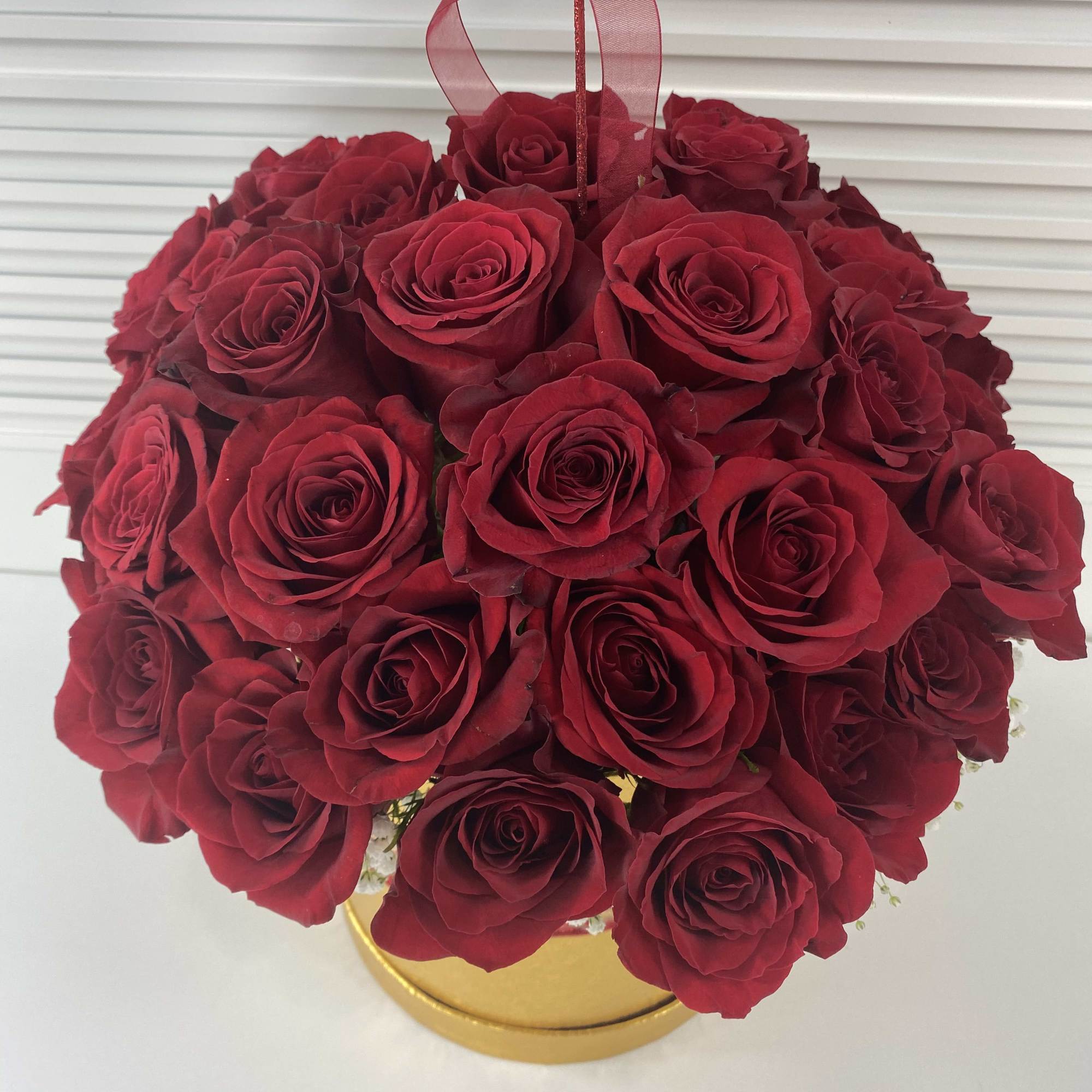 Golden round box with 38-40 red roses surrounded with white baby breath.
