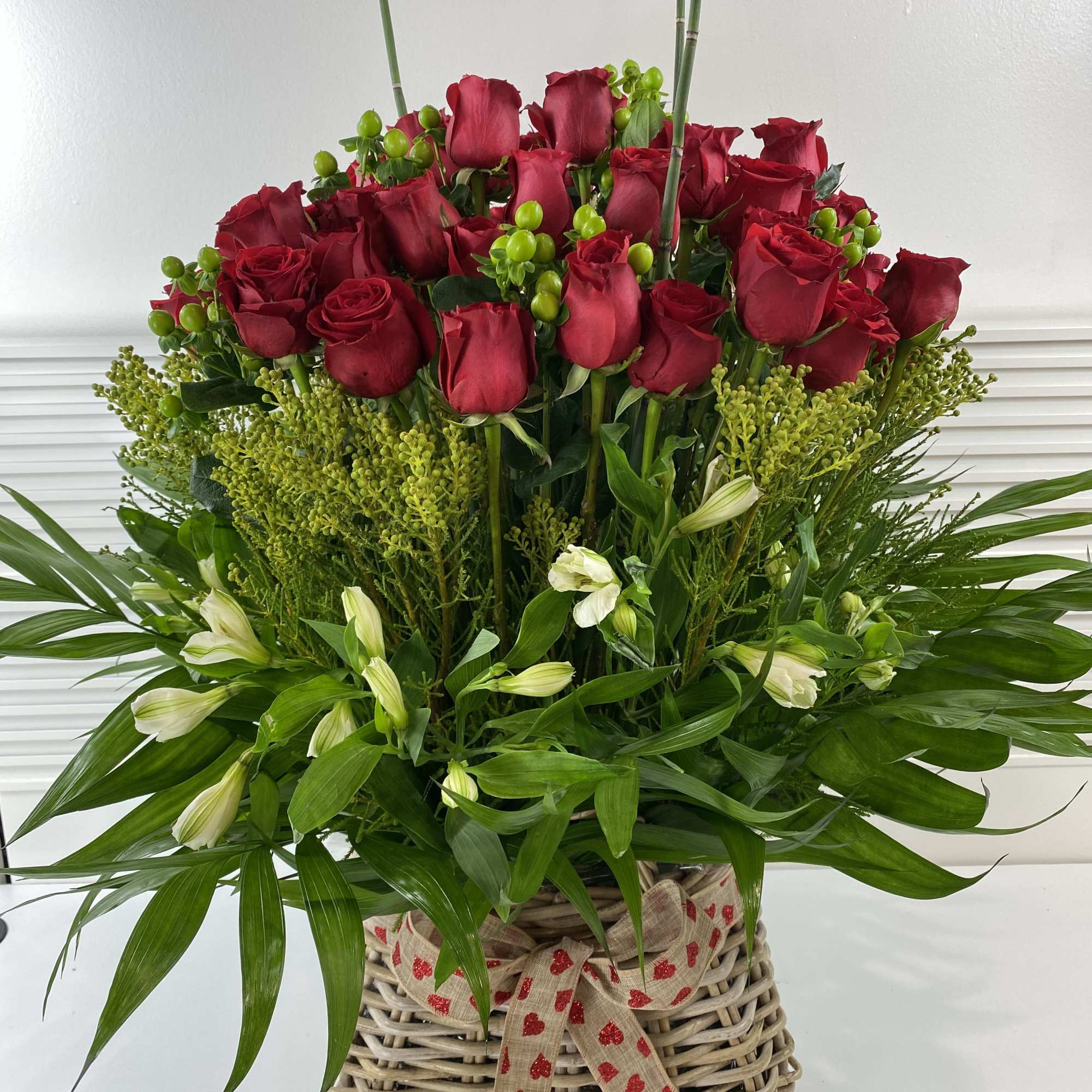 70 long stem red roses and greenery in a rattan big basket