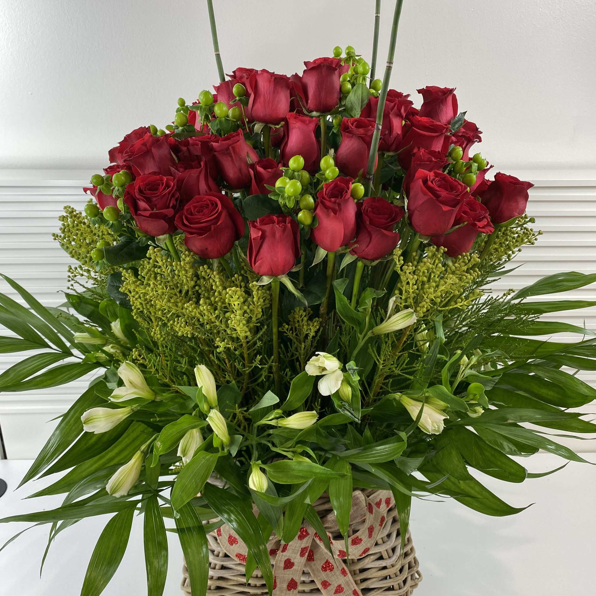 70 long stem red roses and greenery in a rattan big basket