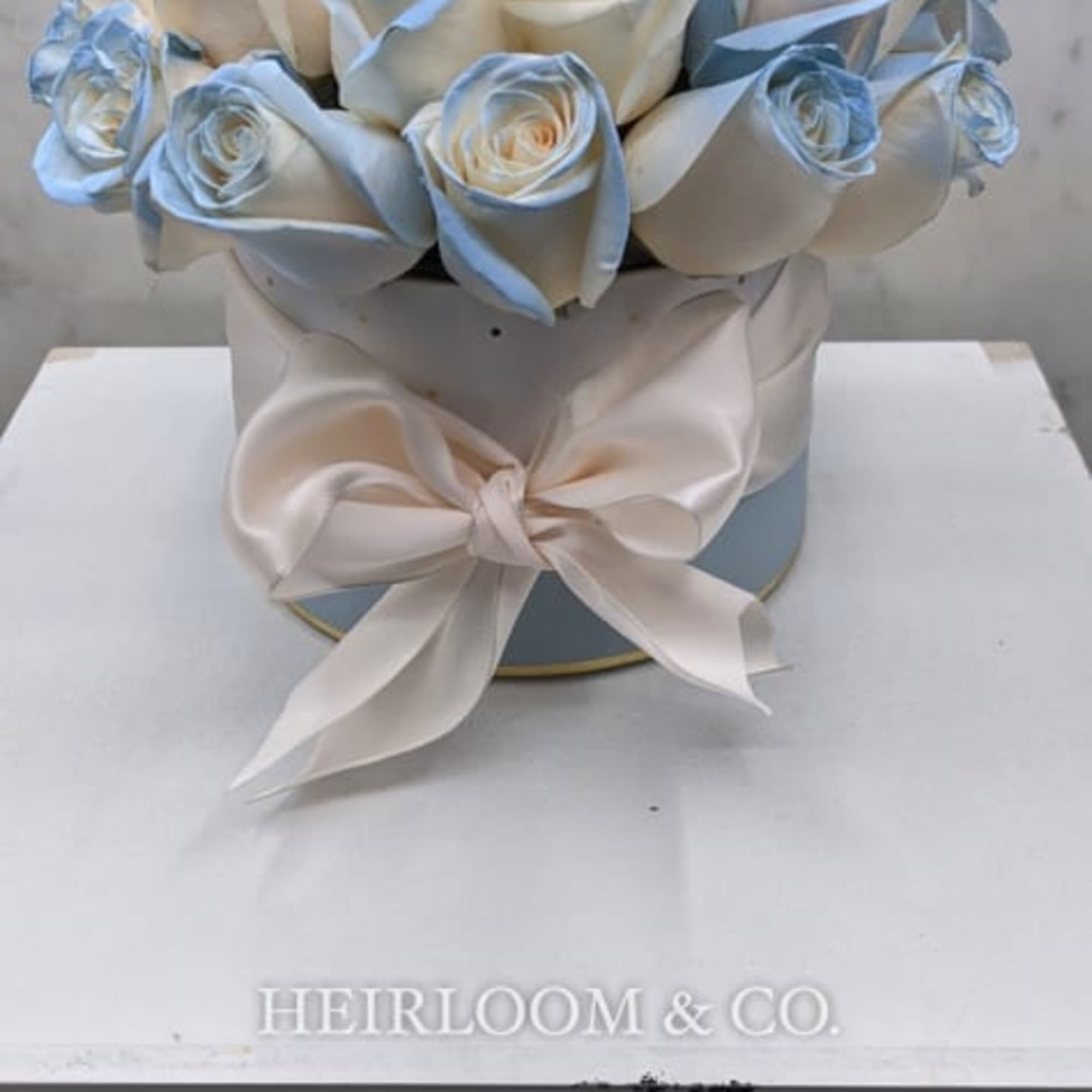 Ingredients:
Premium Ivory Roses with a Blue Pastel Accent
White Hat-Box with Gold Polka