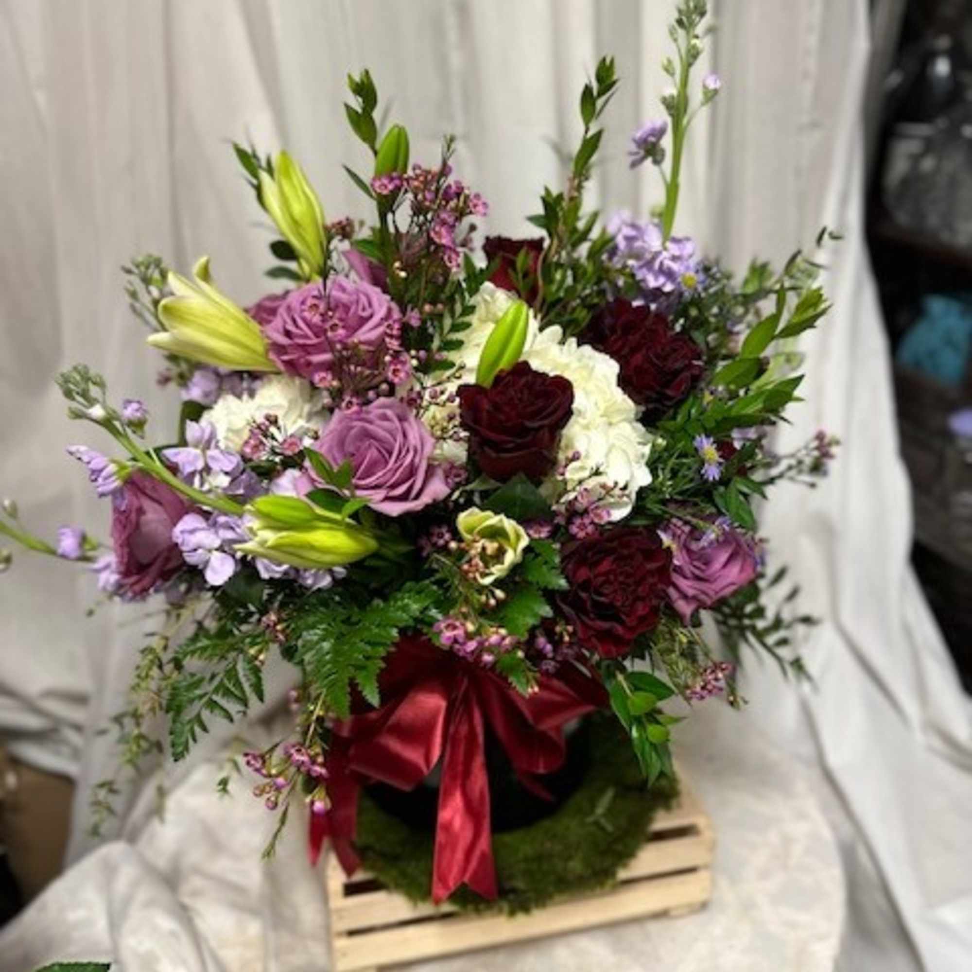A blooming arrangement of purple and red roses with accents of hydrangea