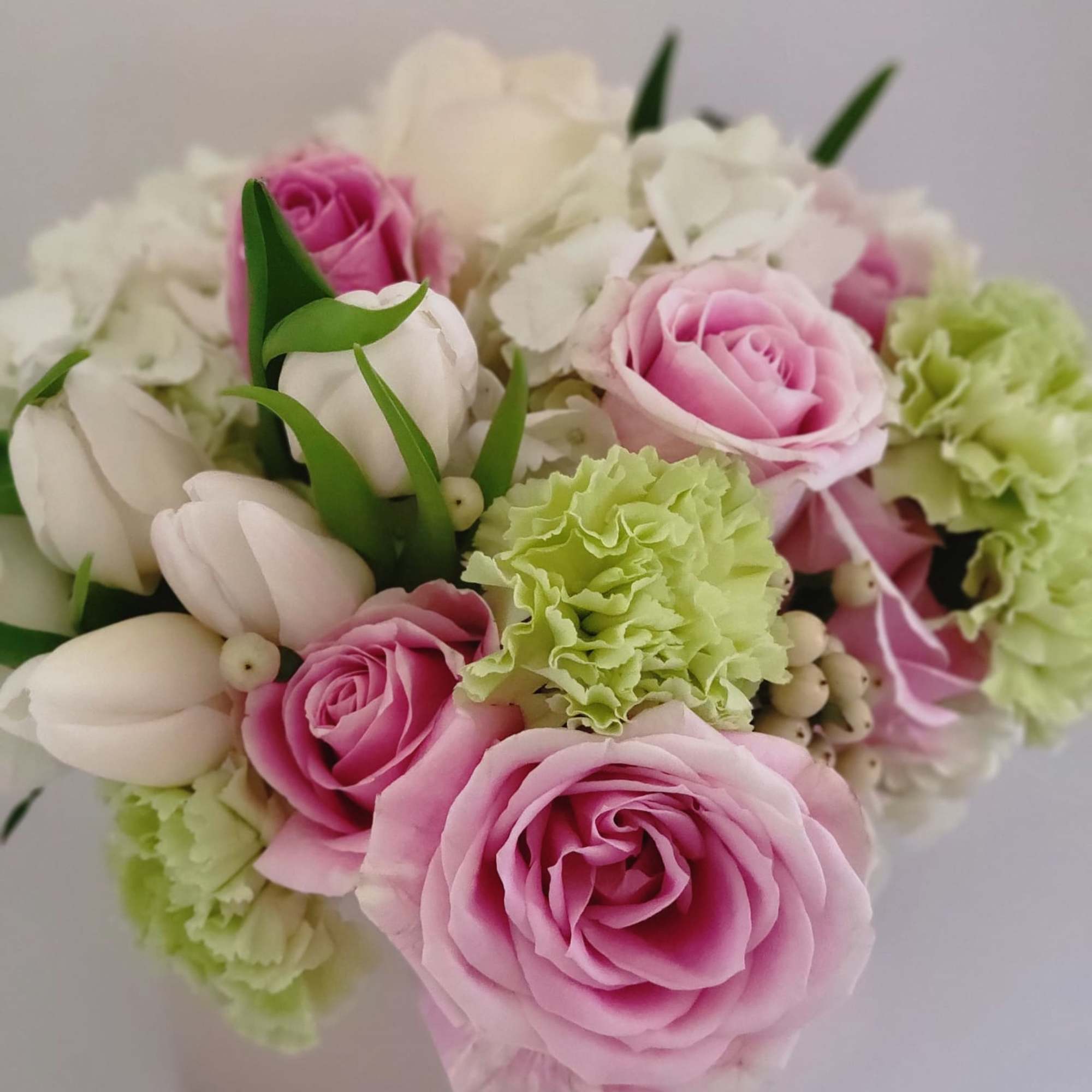 A mixture of soft and calm color arrangement in a cube vase