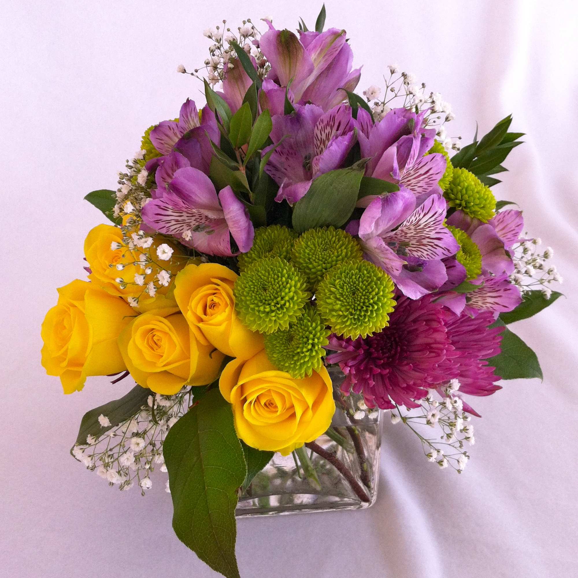 A cube glass vase holding an array of hot pink roses on