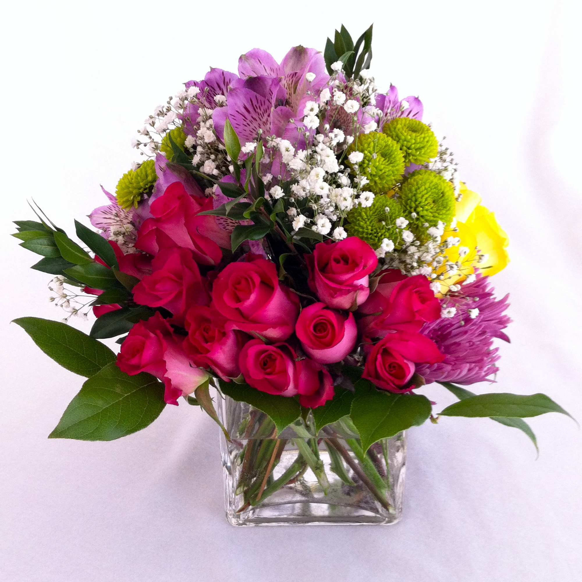 A cube glass vase holding an array of hot pink roses on