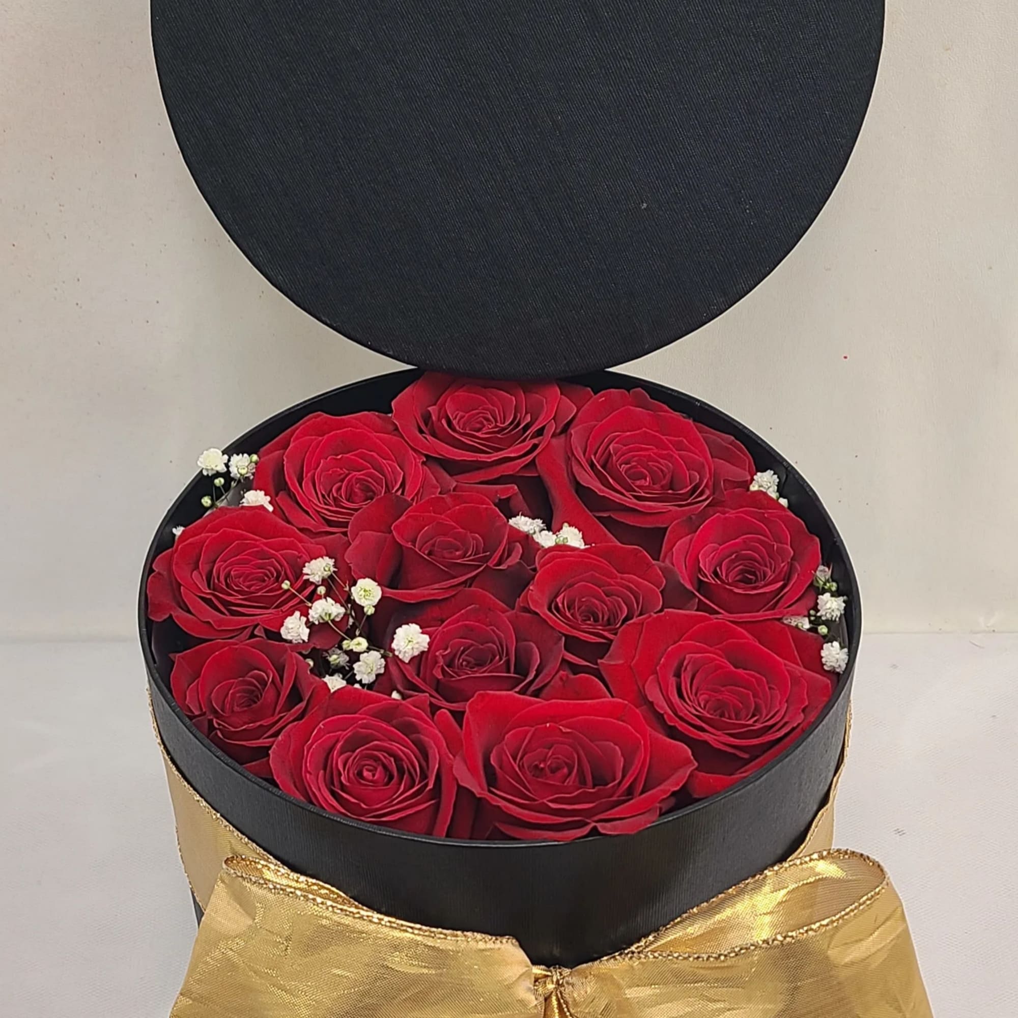Round blank hat box with 12-14 red roses and baby breath. Surprise
